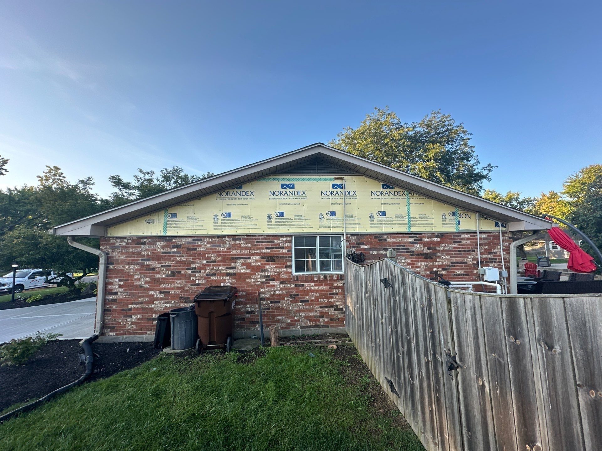 House wrap on the gable above the brick, behind the fence, Beavercreek, Ohio.