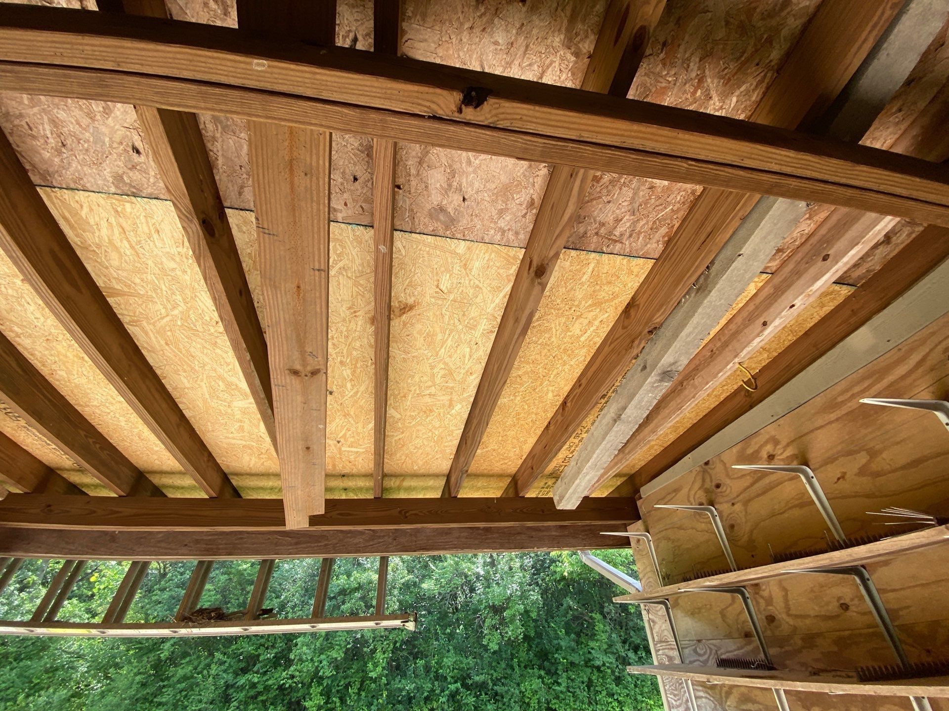 Garage rafters seen from below with new and old decking overhead, Yellow Springs, Ohio.