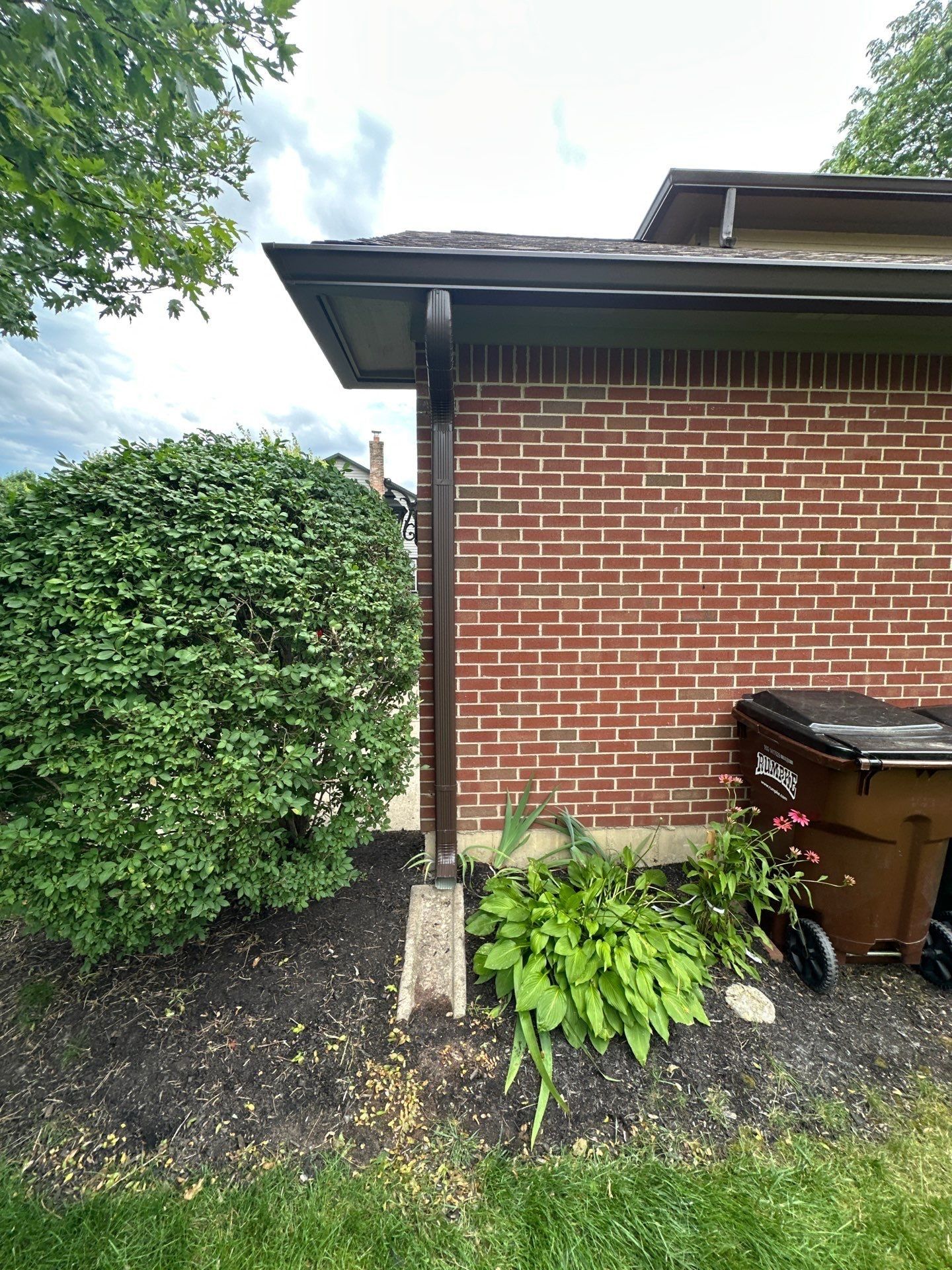 New dark brown seamless gutter and downspout on the brick wall, Beavercreek, Ohio.