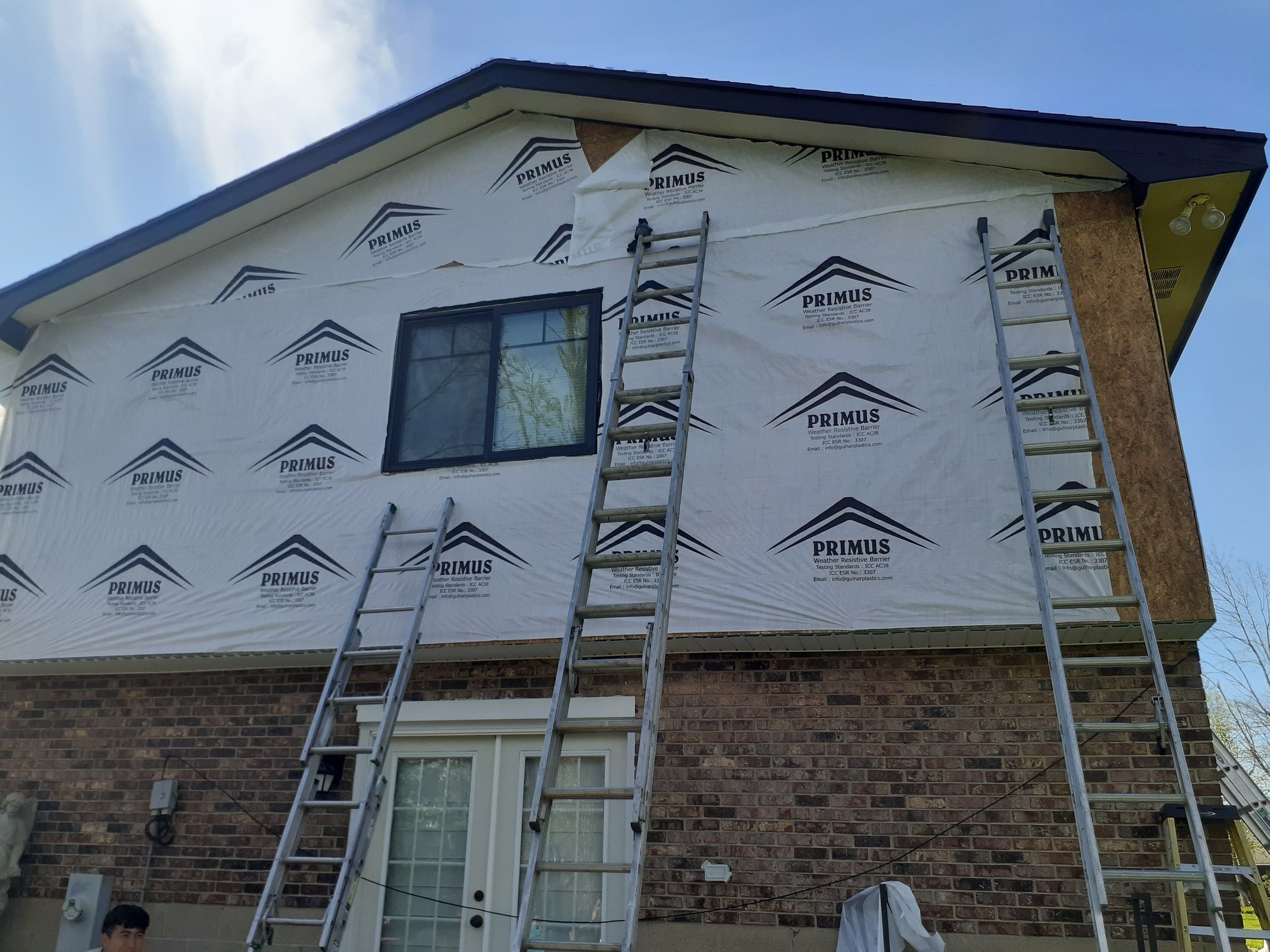 House wrap on the back gable, with ladders below, Beavercreek, Ohio.