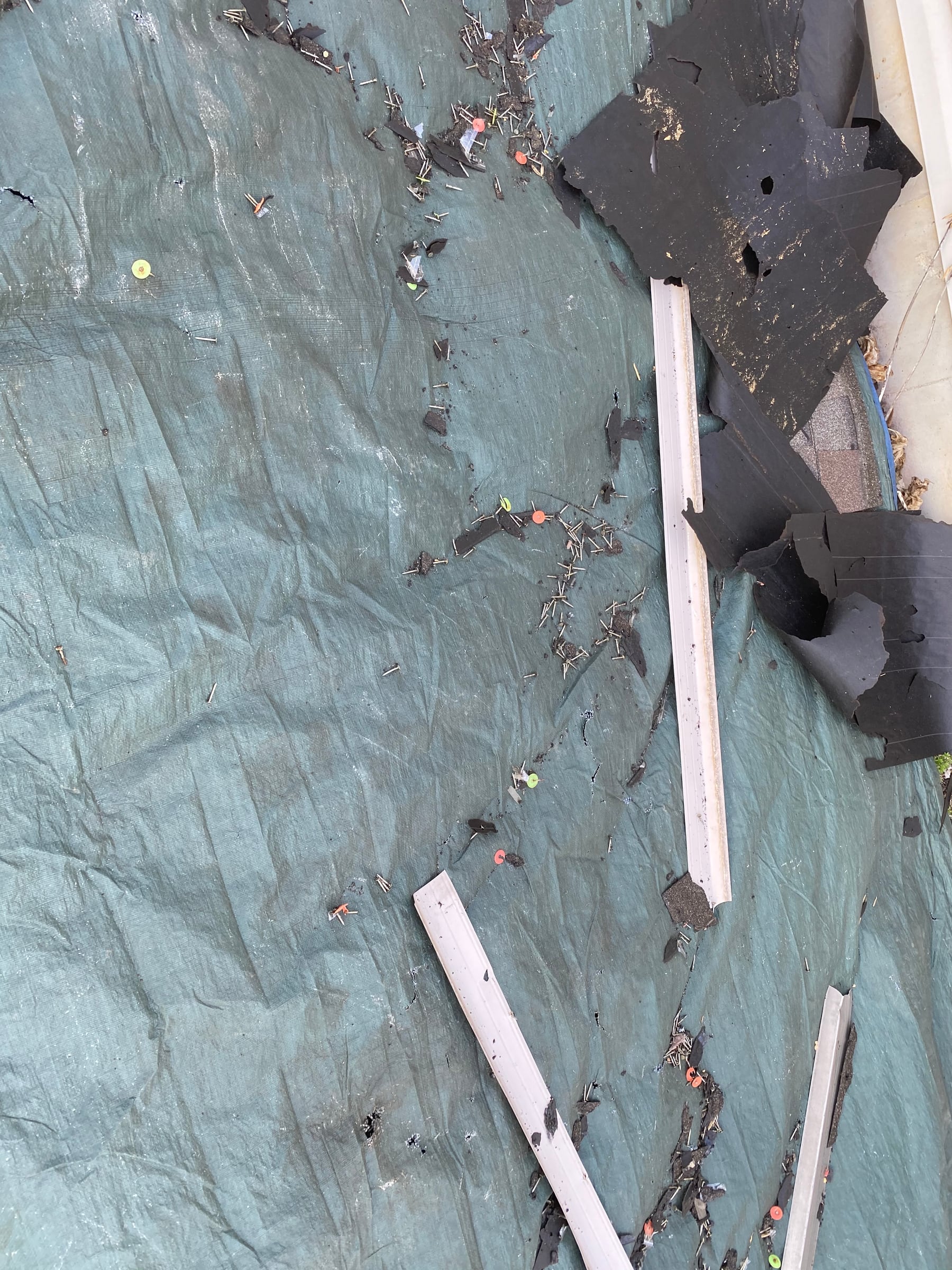 Nails and shingle pieces on a ground tarp