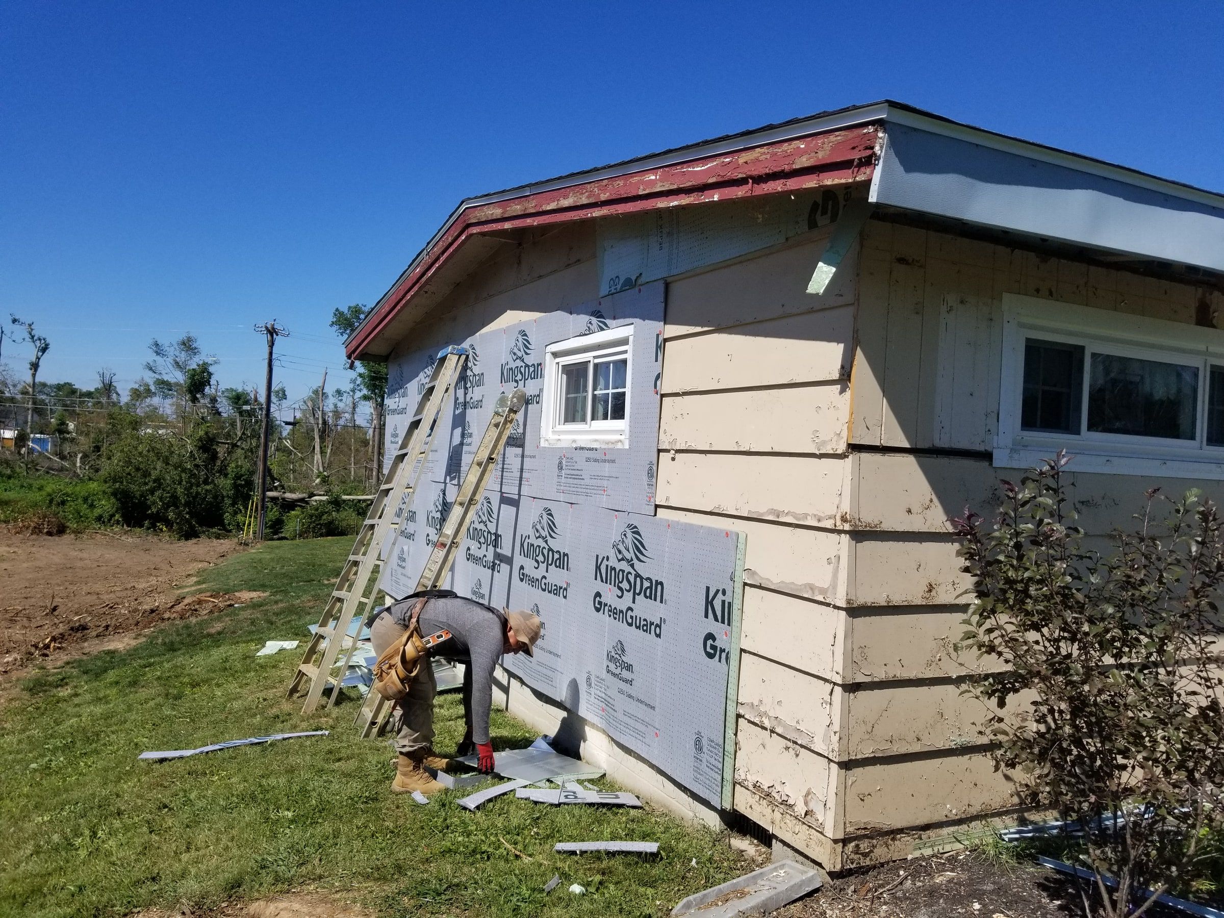 A crew member fastening fanfold board at the corner of the house, Beavercreek, Ohio.