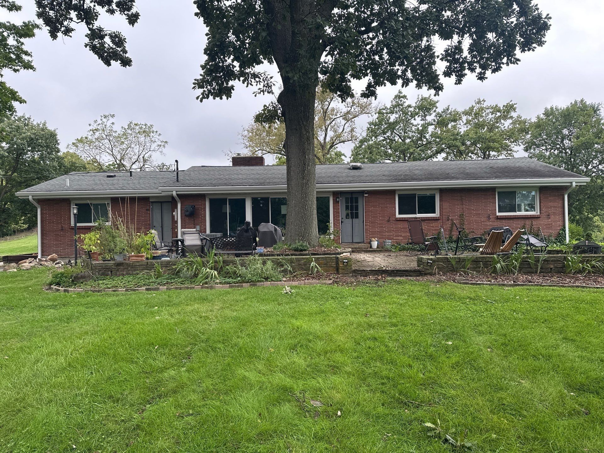 The back of the house across the lawn, with new white gutters along the whole eave.