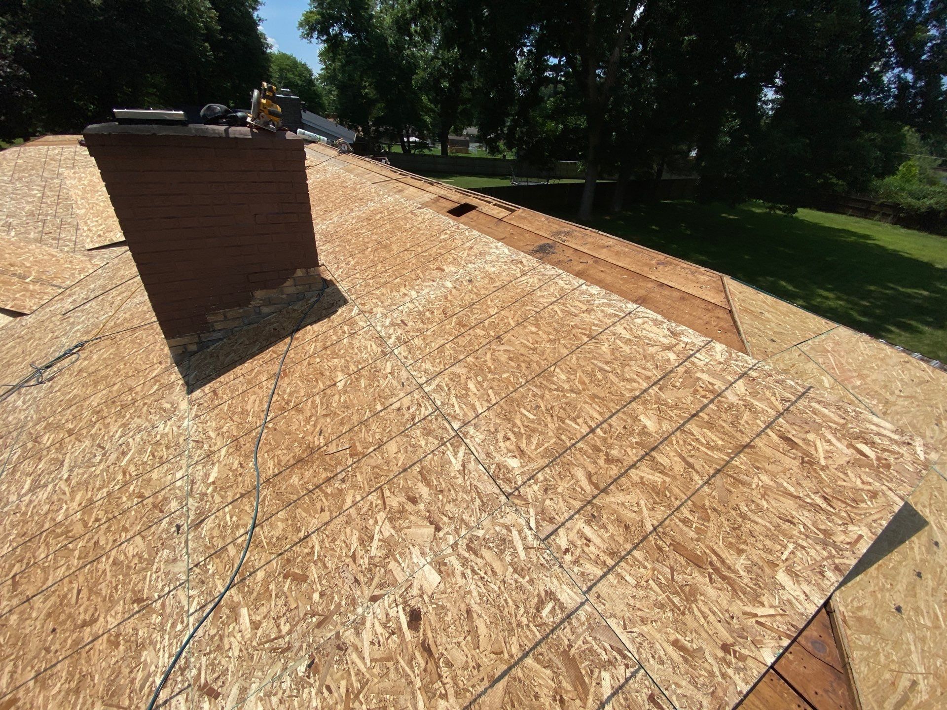 Brick chimney surrounded by newly installed roof sheathing, Beavercreek, Ohio.