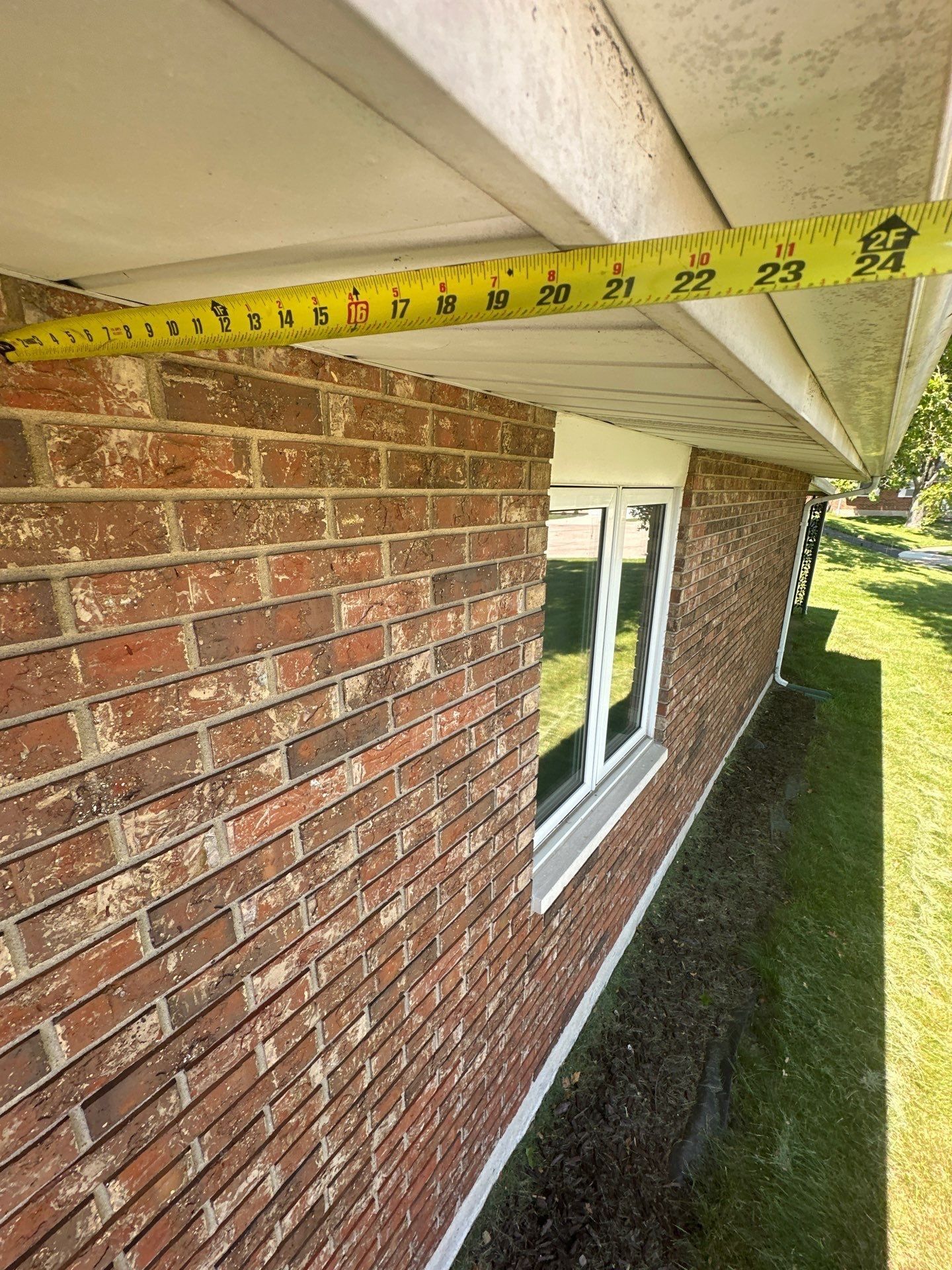 A tape measure held under the soffit to measure the roof overhang, West Carrollton, Ohio.