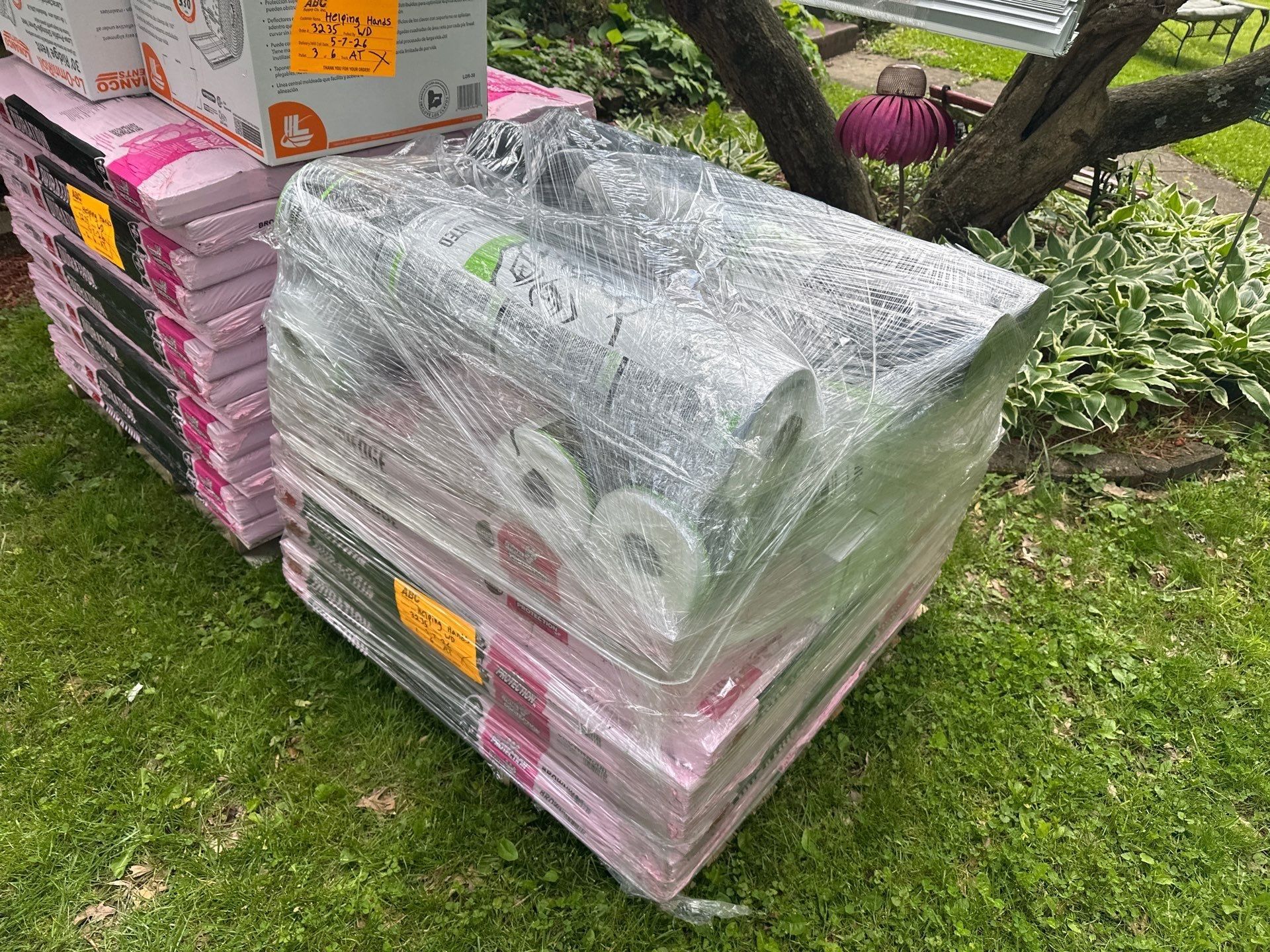 Shingle pallets and underlayment rolls on grass