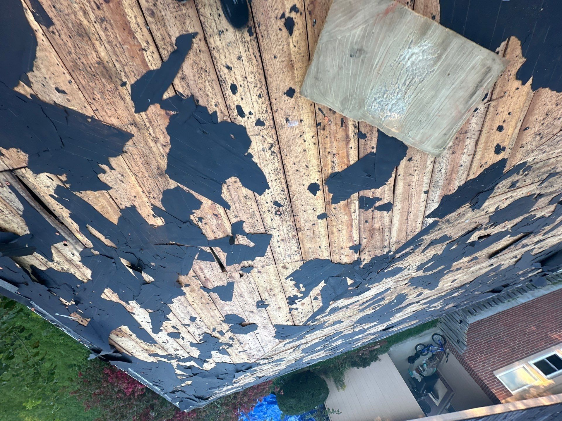 Old shingle scraps on the plank deck halfway through the tear-off, Kettering, Ohio.