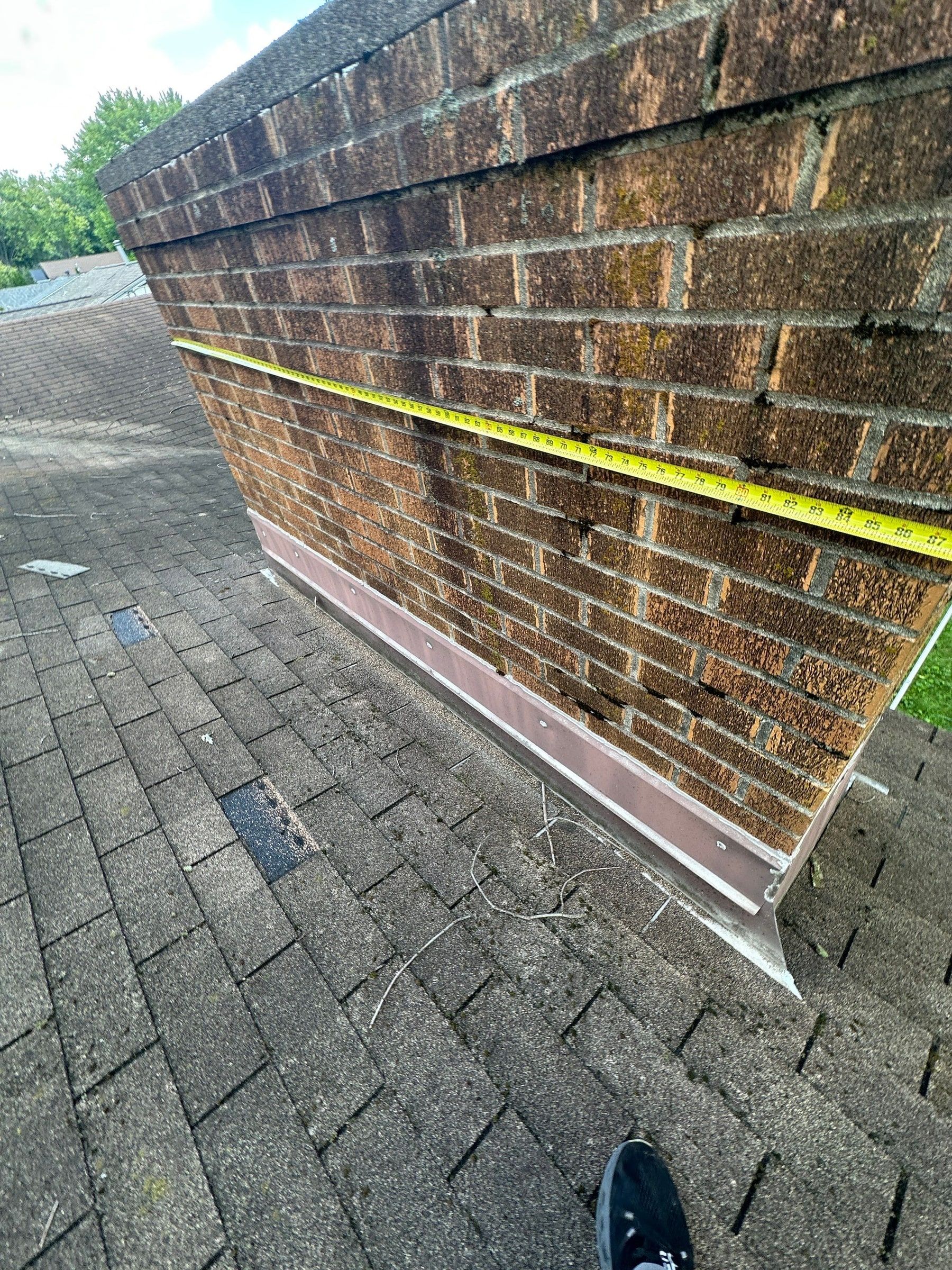 A tape measure along the brick chimney on the roof, Kettering, Ohio.
