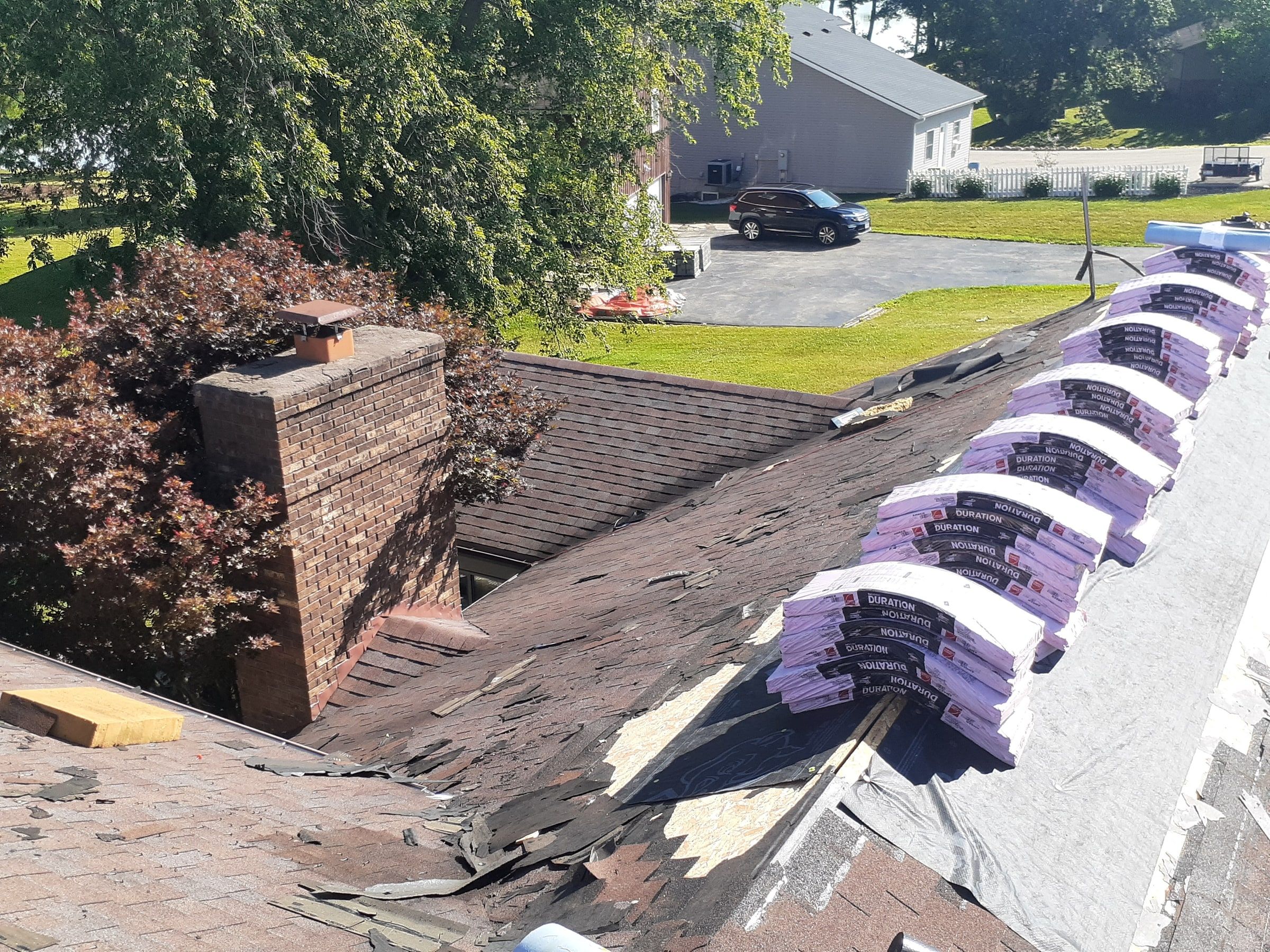 Shingle bundles lined along the ridge near the chimney during tear-off, Jamestown, Ohio.