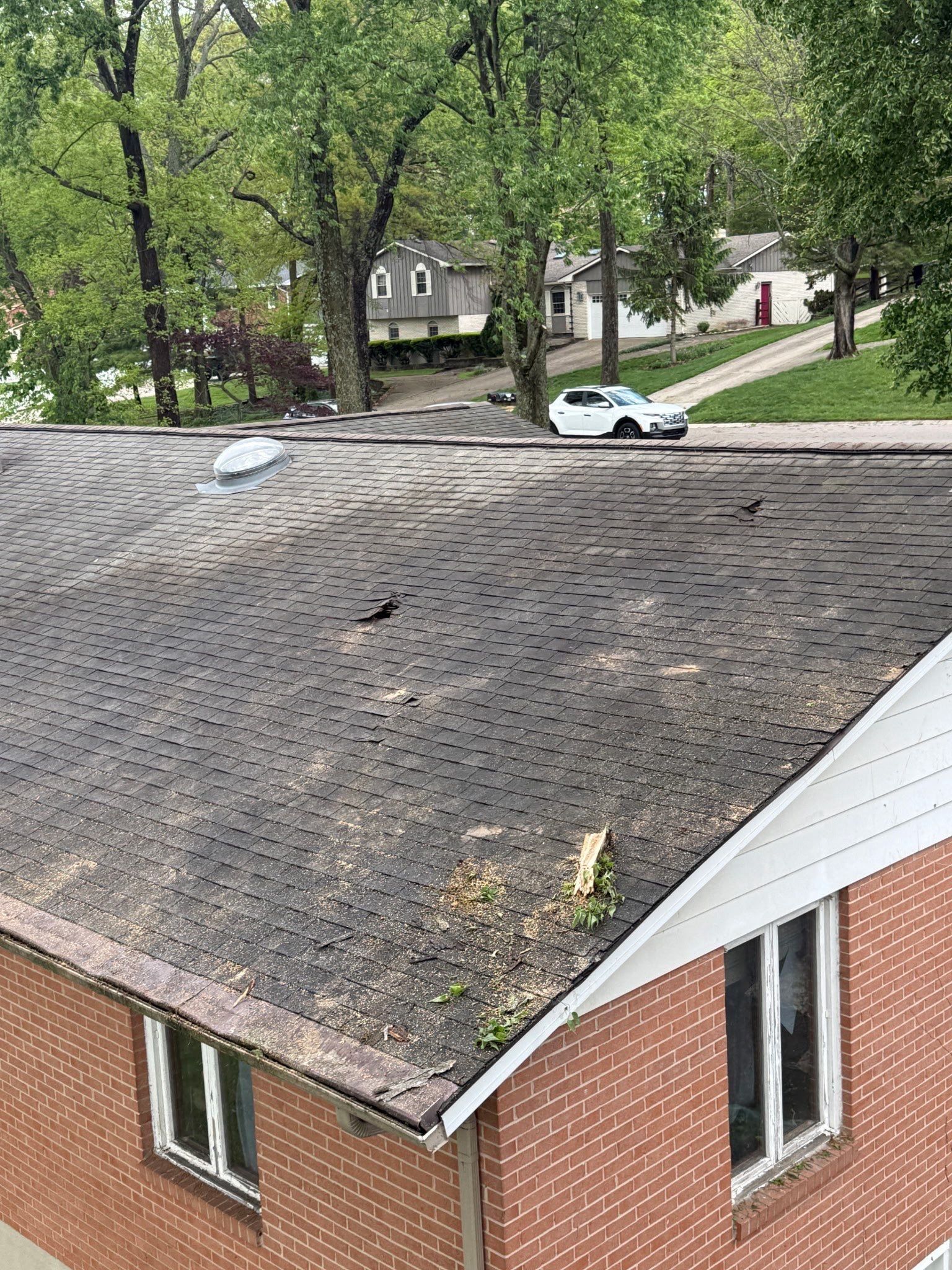 The roof after the tree came off, with broken shingles and debris near the eave, Beavercreek, Ohio.