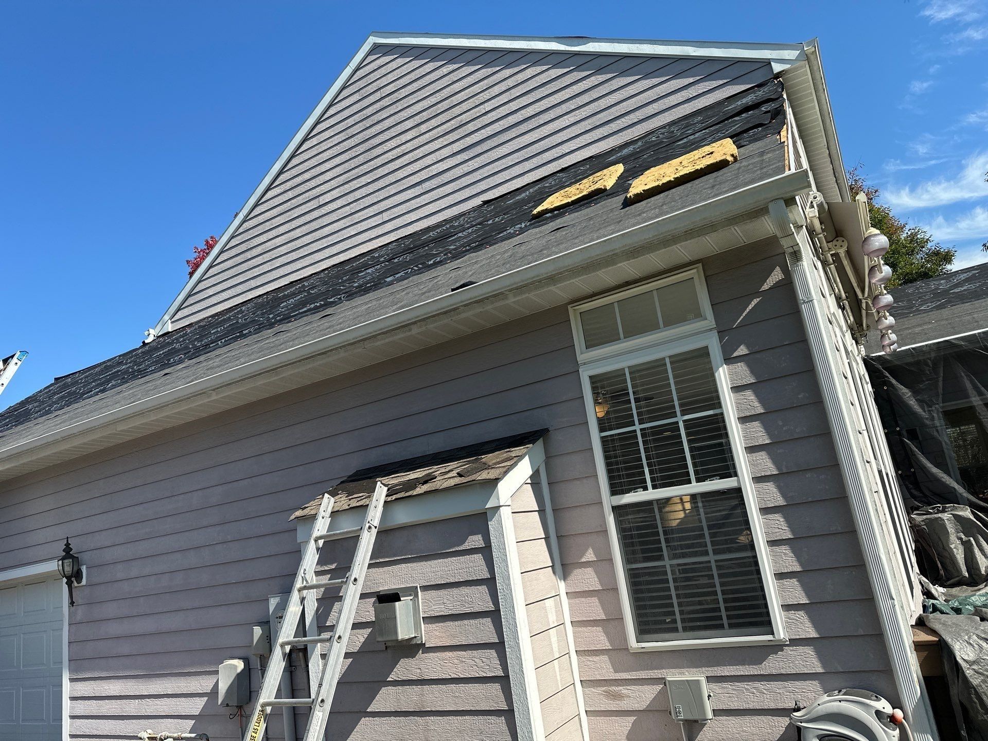 Ladders against the side wall as the old shingles come off the lower roof, Beavercreek, Ohio.