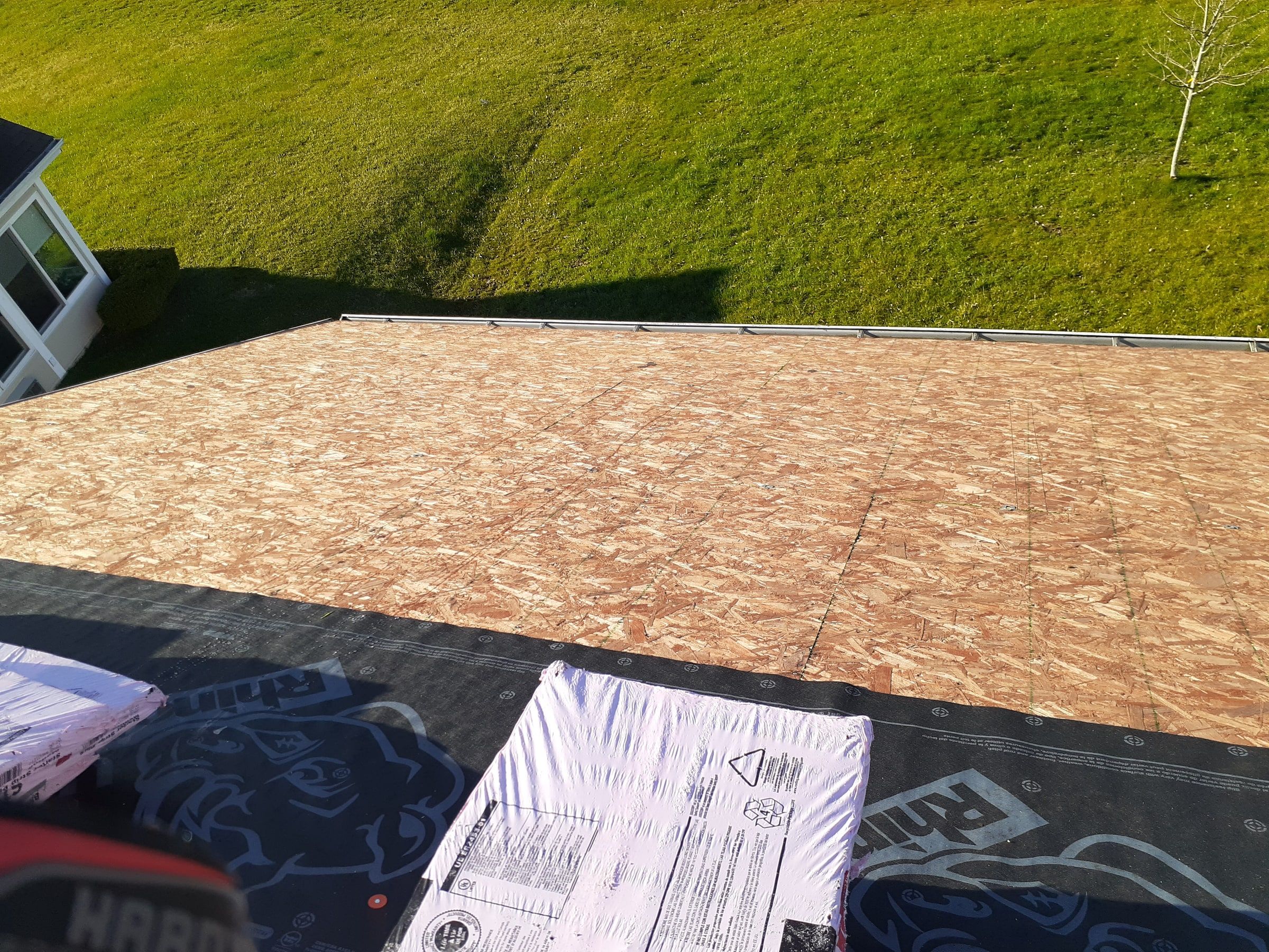 Bundles staged on the underlayment at the top of the roof, with the bare OSB deck below, Xenia, Ohio.