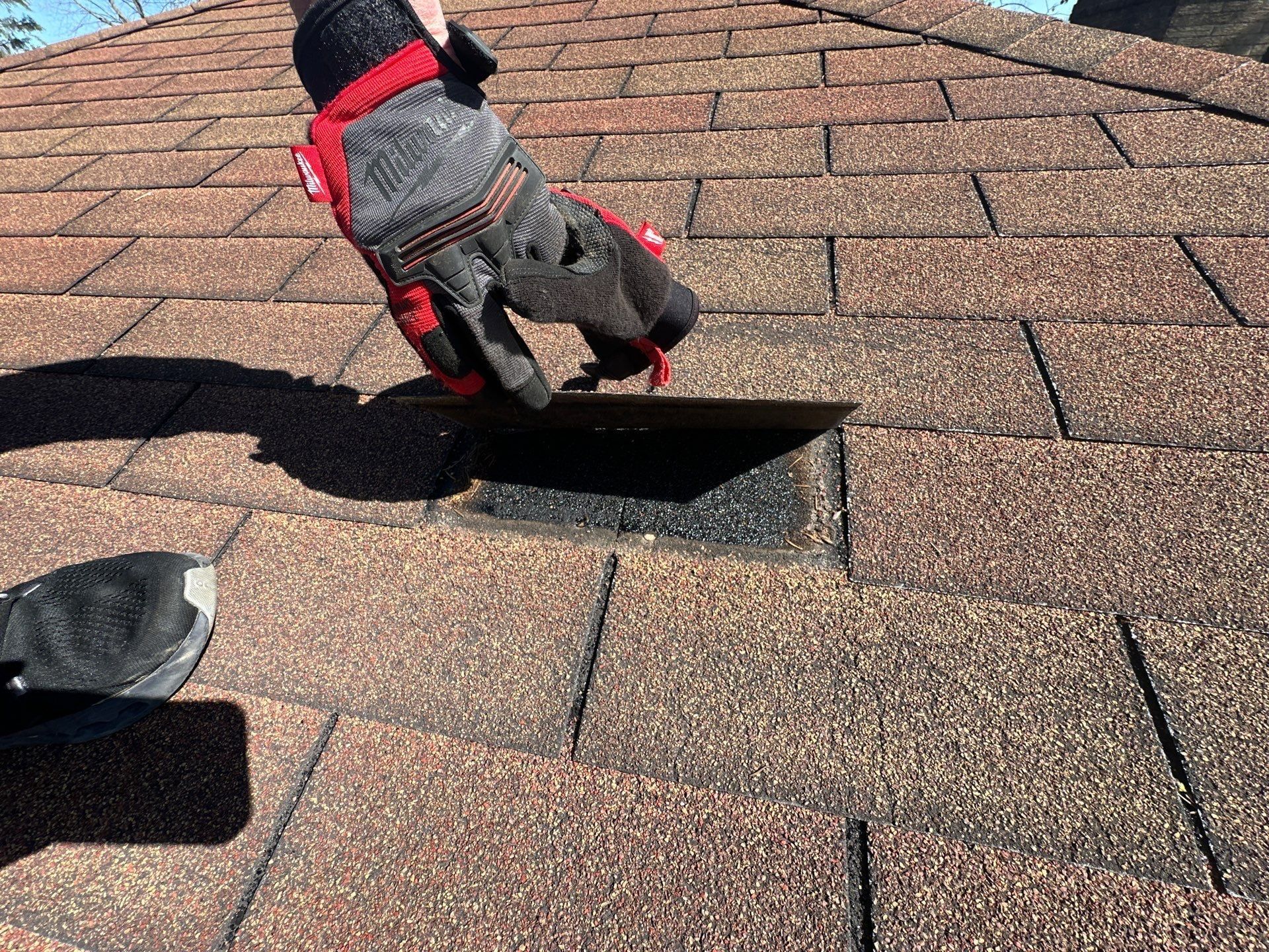 Gloved hand lifting a loose shingle to show where wind broke it free, Beavercreek, Ohio.