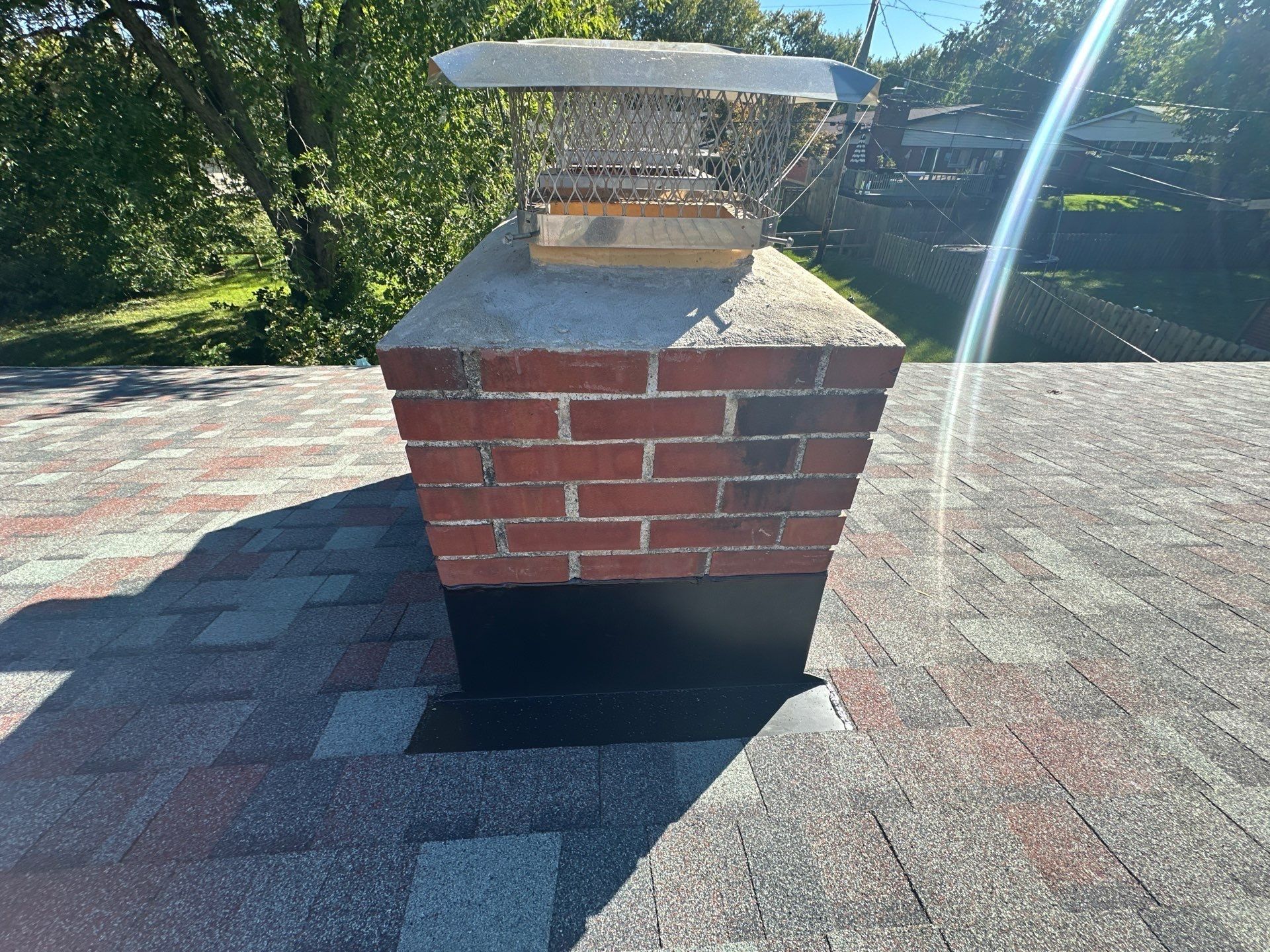 The chimney with its cap and new black flashing on the finished roof, Kettering, Ohio.