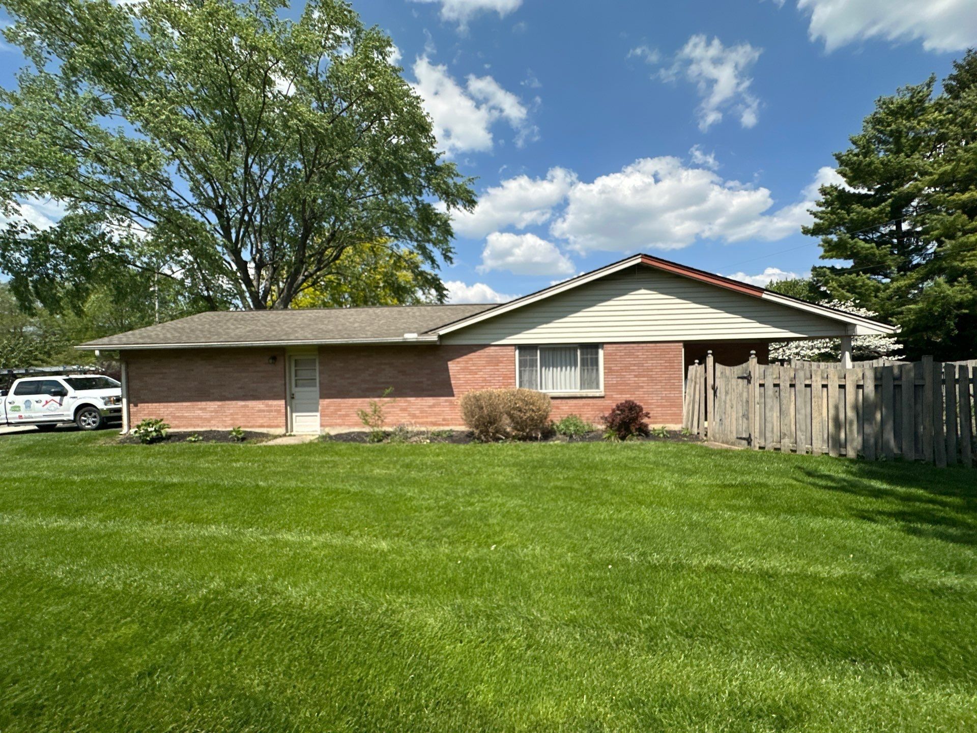 The brick ranch from the yard, with damage on another gable, Kettering, Ohio.