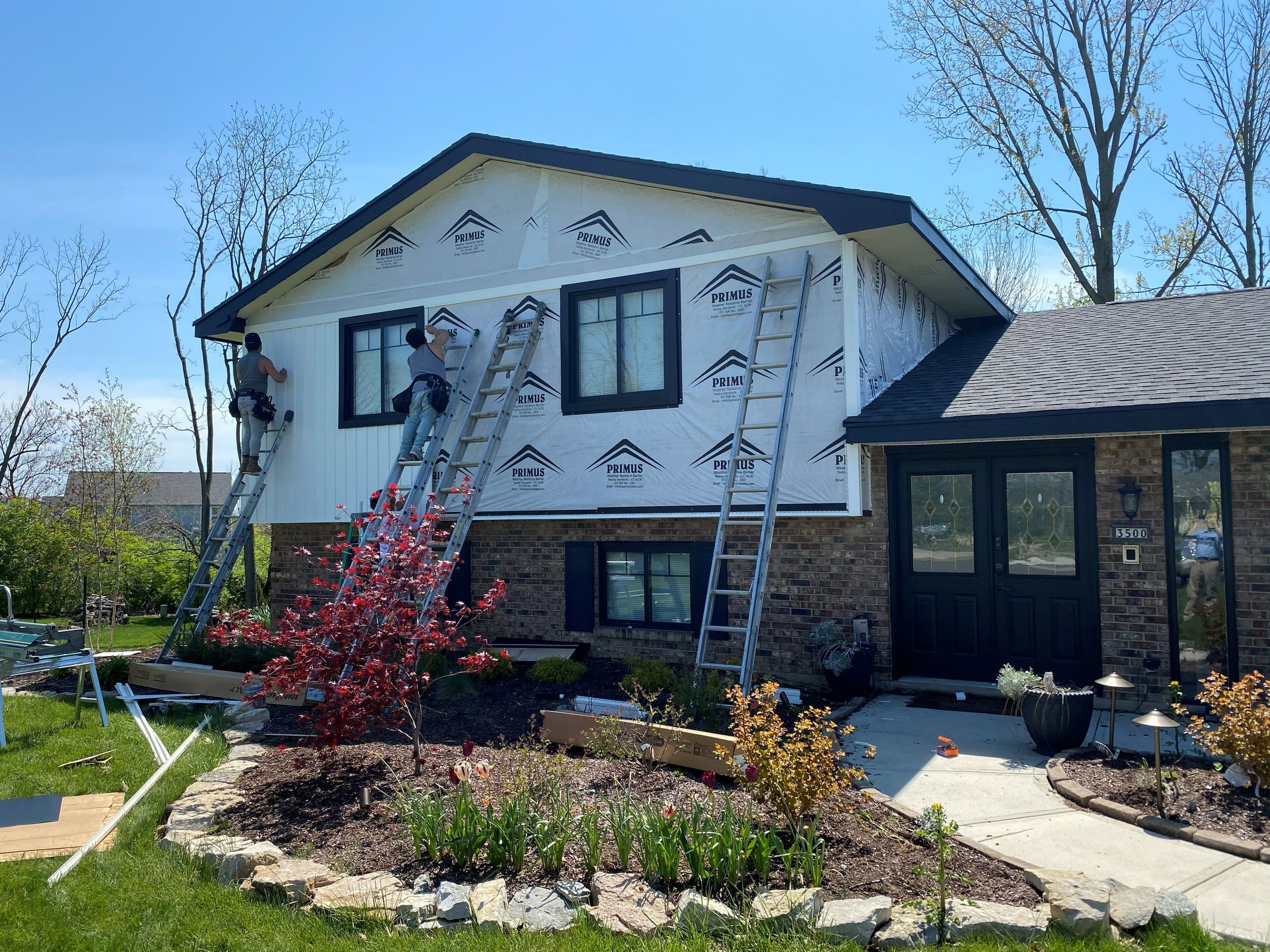 New white board-and-batten siding going up on the front, the crew on ladders, Beavercreek, Ohio.