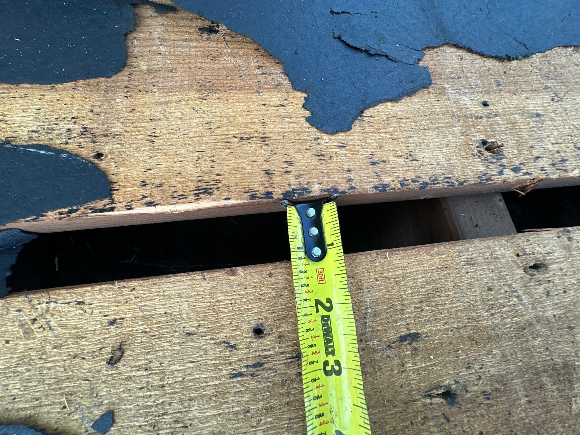 Wide gap between deck boards measured with a tape after tear-off, Beavercreek, Ohio.