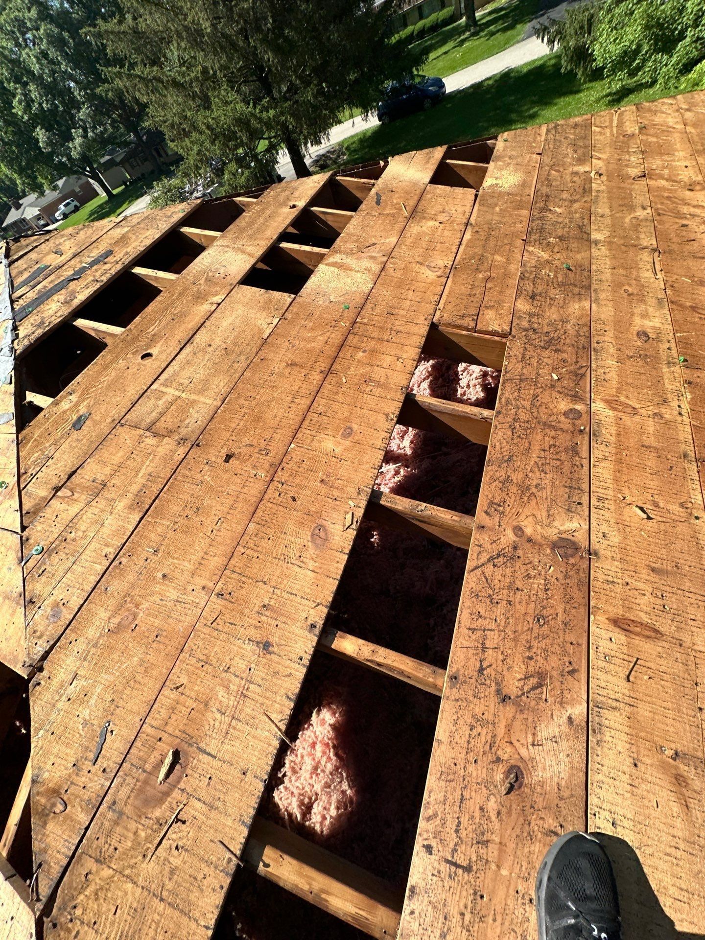 Open gaps between the old deck boards showing rafters and insulation, Beavercreek, Ohio.