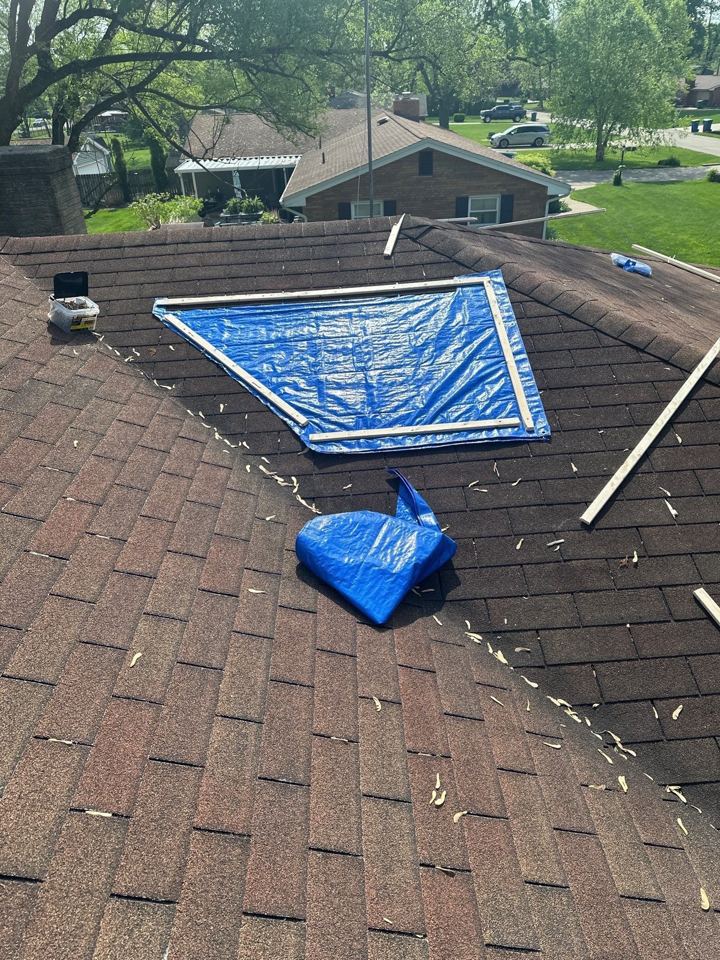 Blue emergency tarp being fastened over a damaged area of the roof, Beavercreek, Ohio.