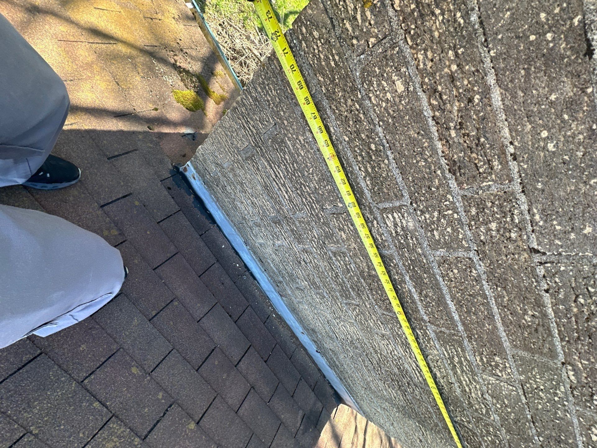 Tape measure run up the chimney side to size the flashing work, Beavercreek, Ohio.