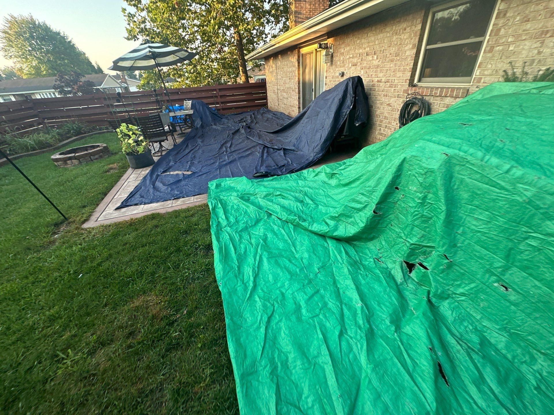 A green tarp and a navy tarp protecting the back patio and grill, Dayton, Ohio.