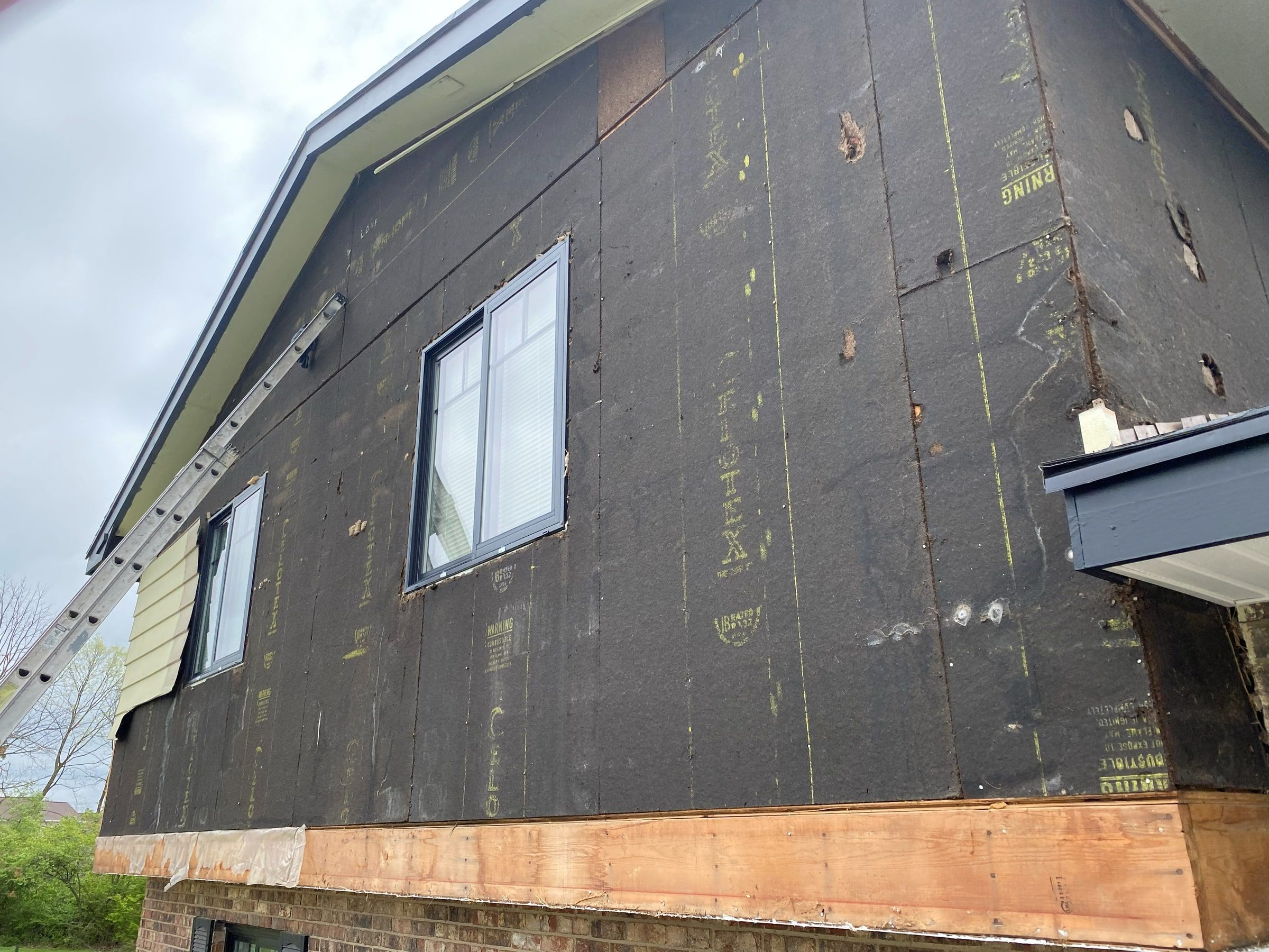 Builder board on the side wall, patched and coming loose above the brick, Beavercreek, Ohio.