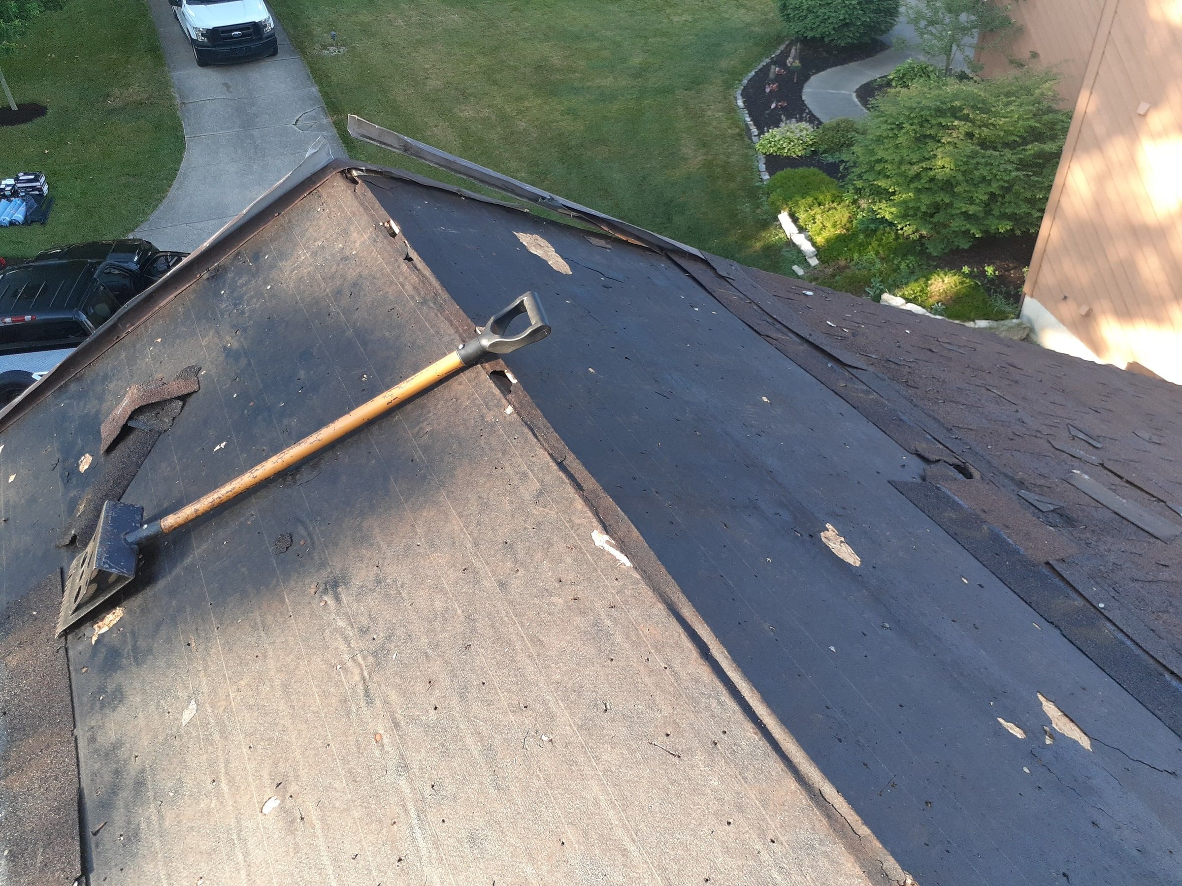 Roofing shovel resting on the old underlayment partway through tear-off, Jamestown, Ohio.