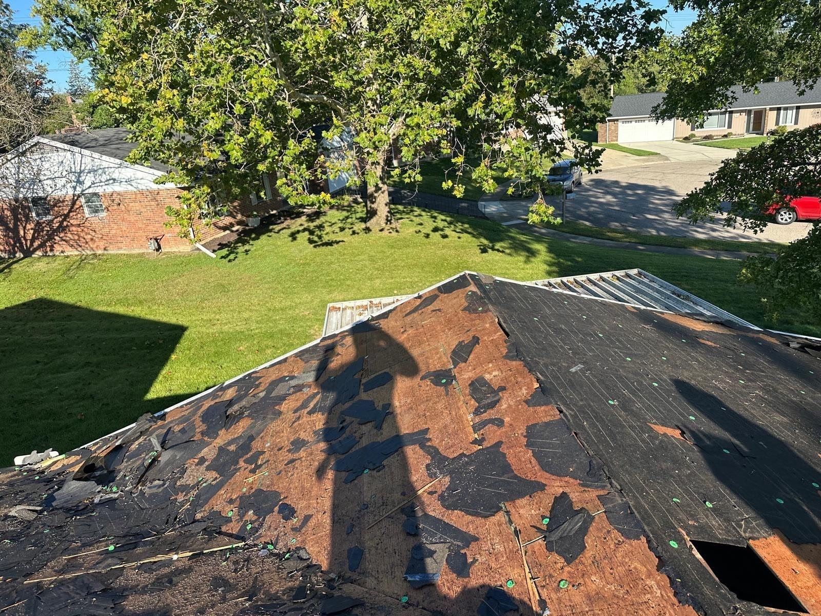 A hip of the lower roof torn off, with old underlayment still in places, West Carrollton, Ohio.