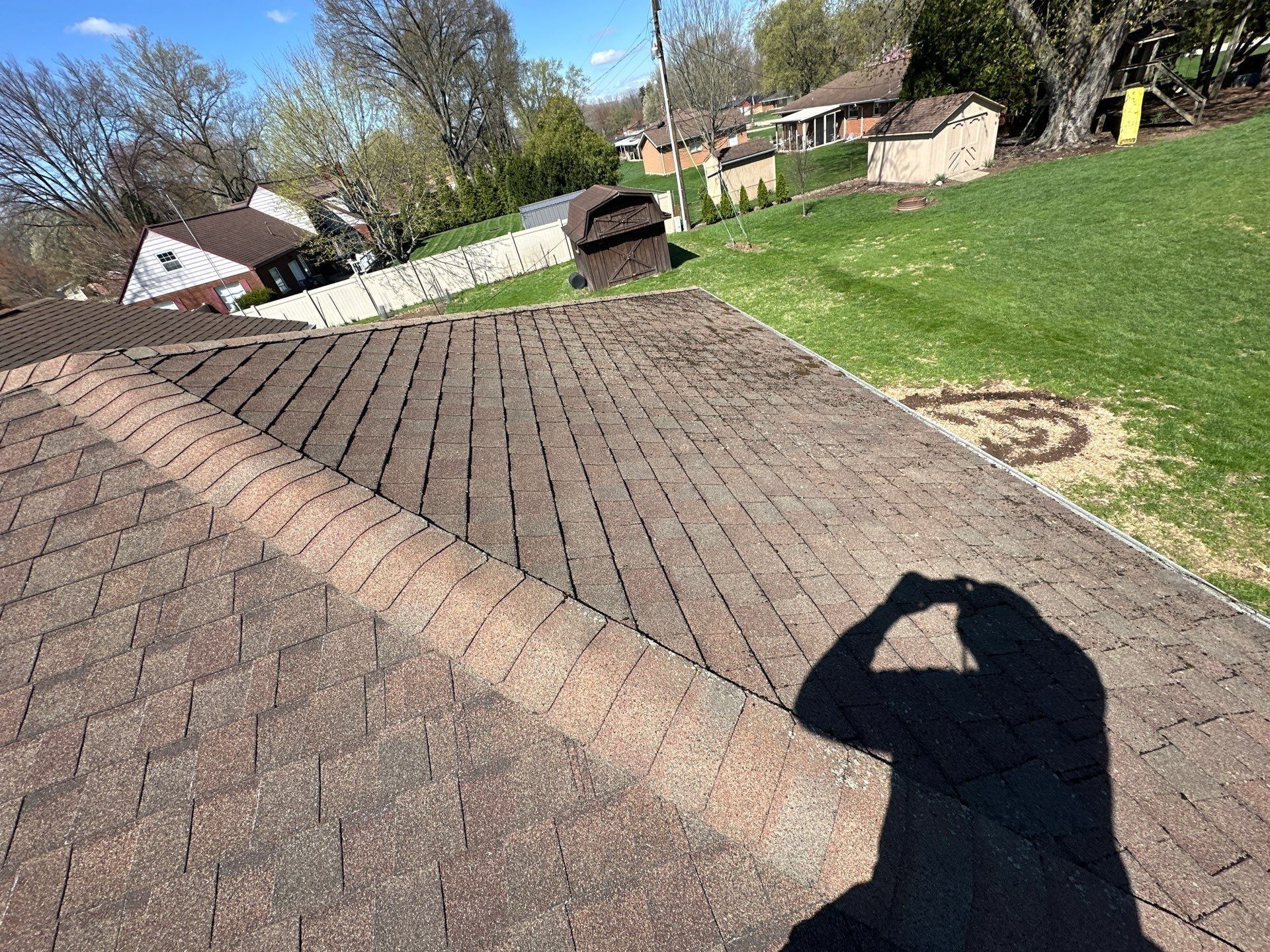 Worn hip ridge caps on the old roof with the inspector shadow, Beavercreek, Ohio.