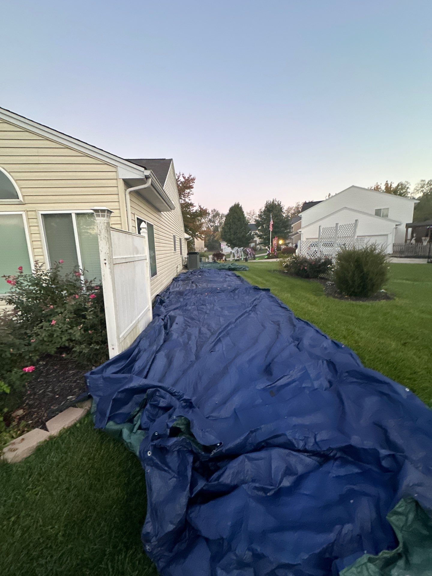 A blue tarp along the side of the house over the landscaping, Beavercreek, Ohio.