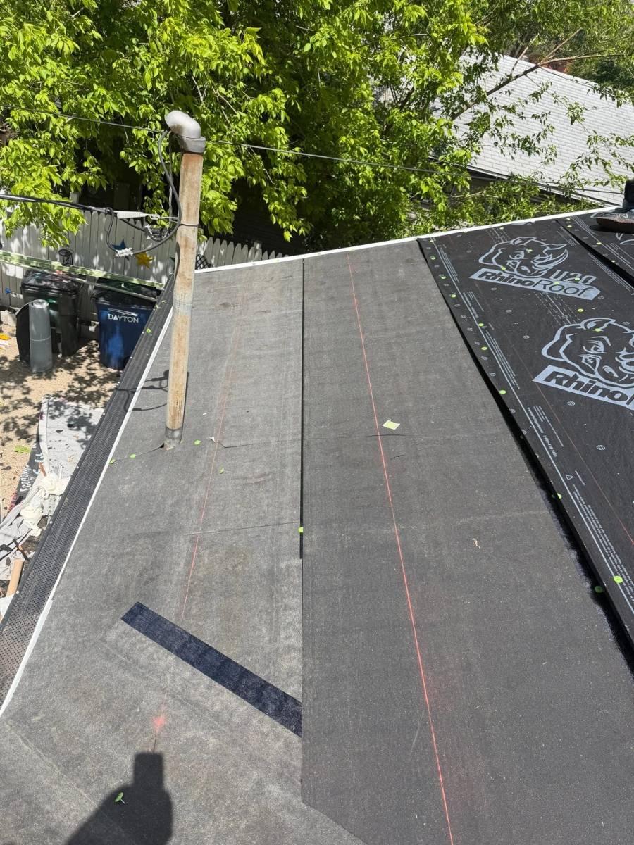 New synthetic underlayment running up one roof slope, chalk lines snapped.