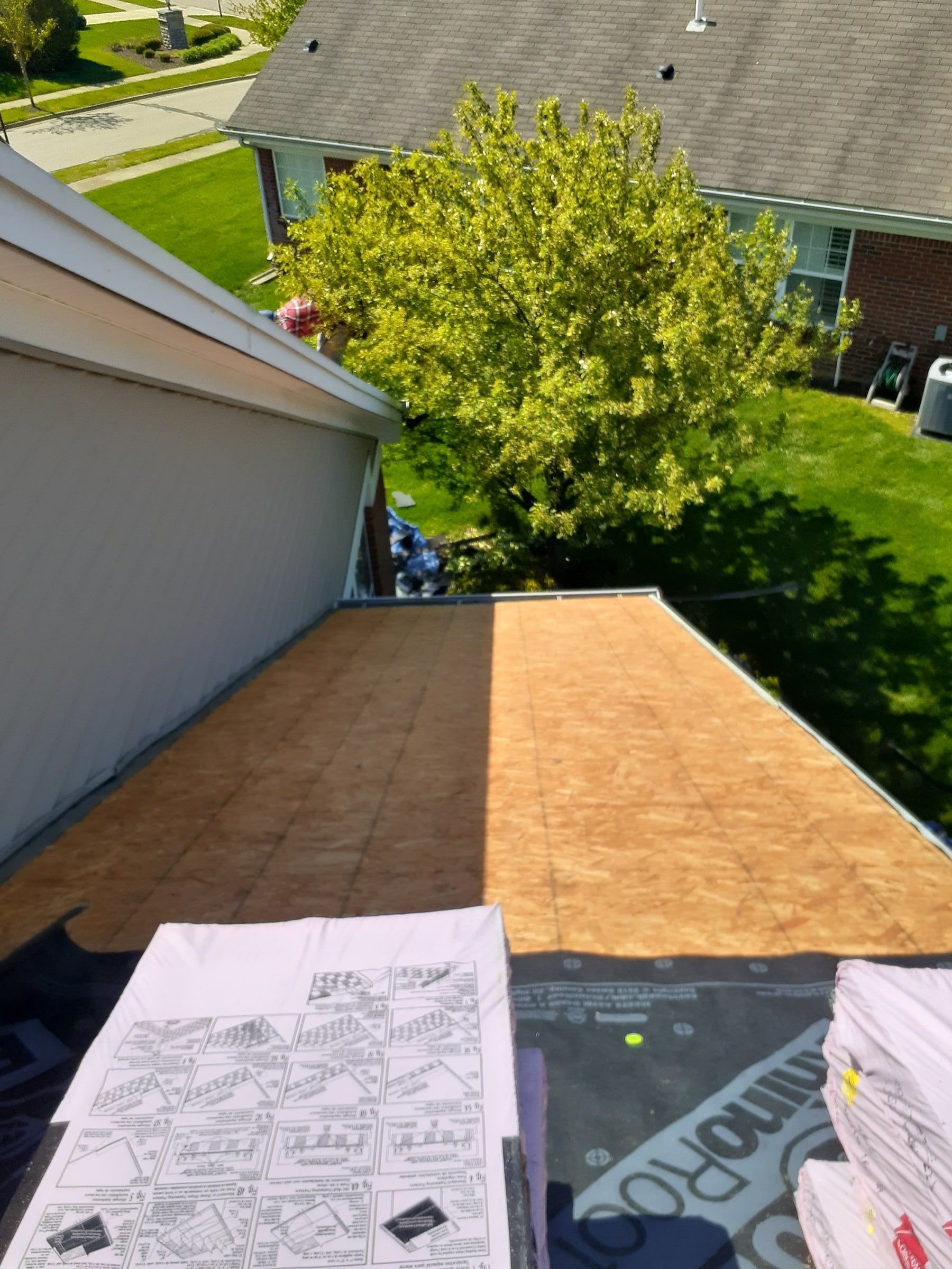 A stripped OSB slope beside the siding, with the yard below, Xenia, Ohio.