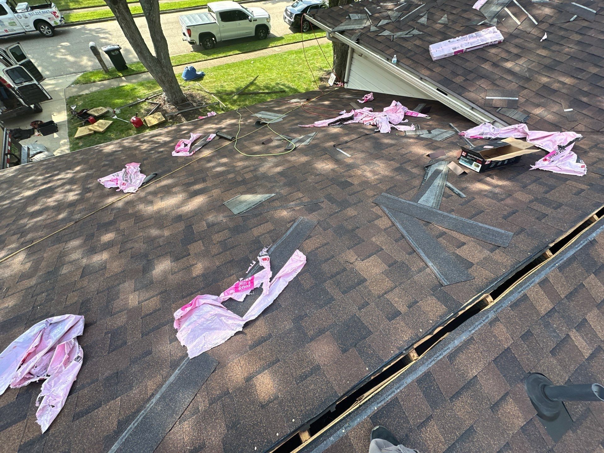 New shingles over the front slope during the install, with a truck on the street, Dayton, Ohio.