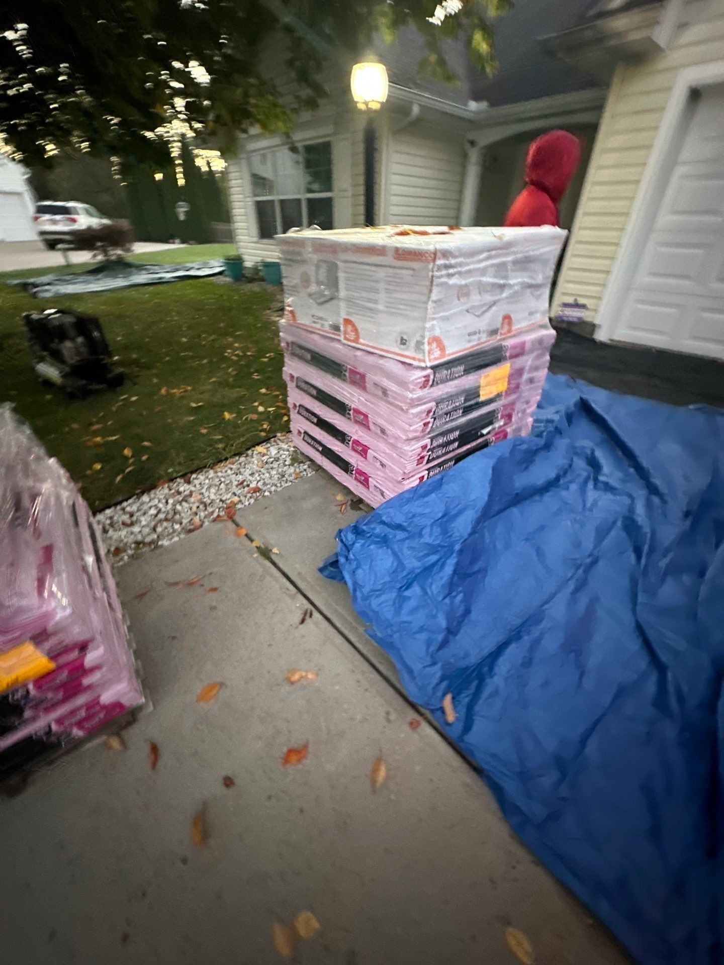 Shingle bundles stacked on the driveway beside a blue tarp, Beavercreek, Ohio.