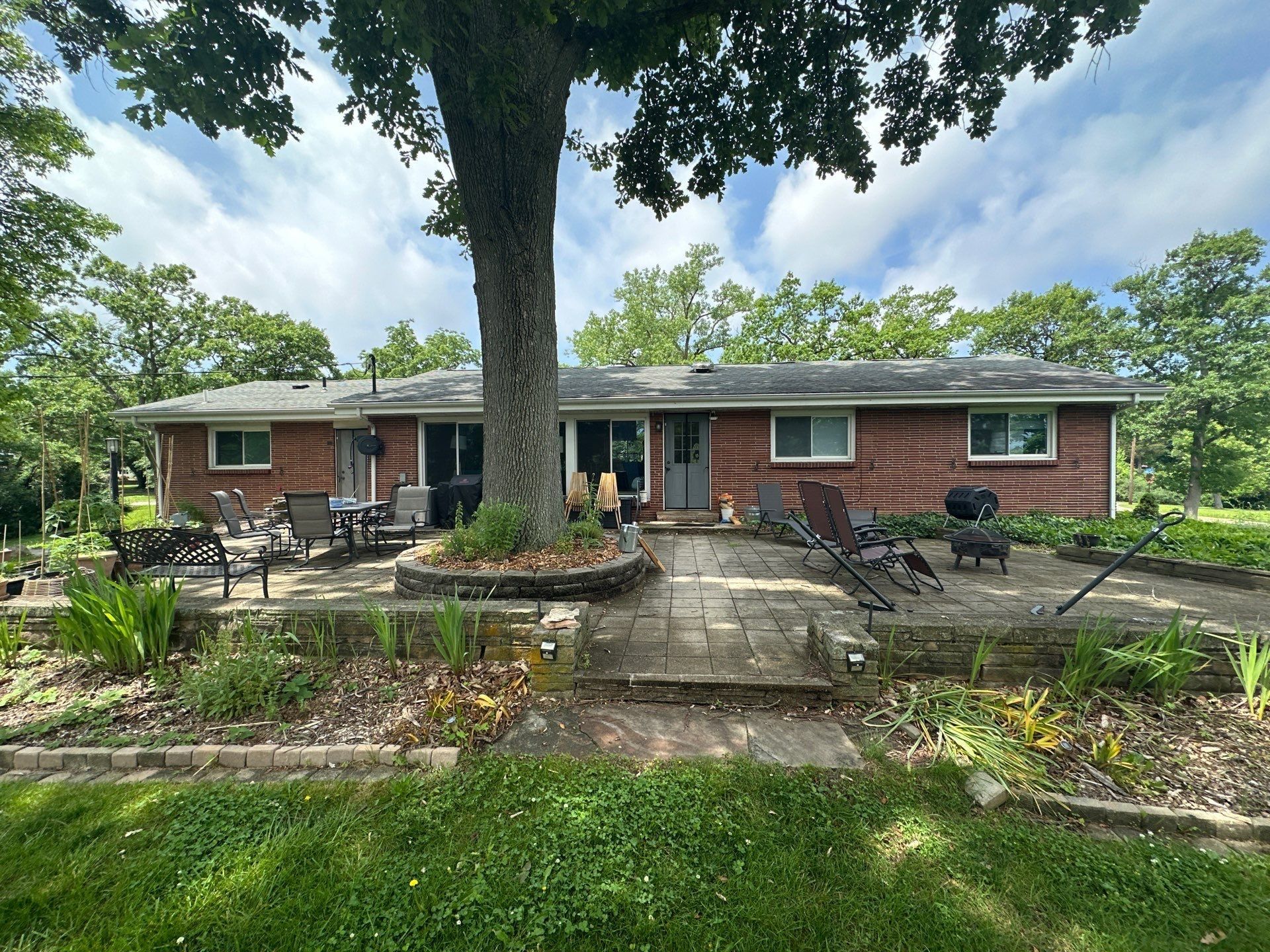 The back of the house across the patio and the oak, with the old gutters along the eave.