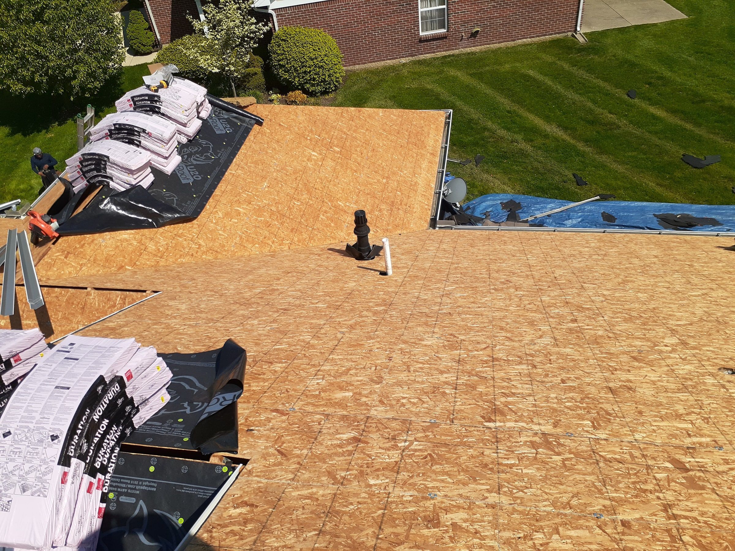 Worker, new sheathing and shingle bundles