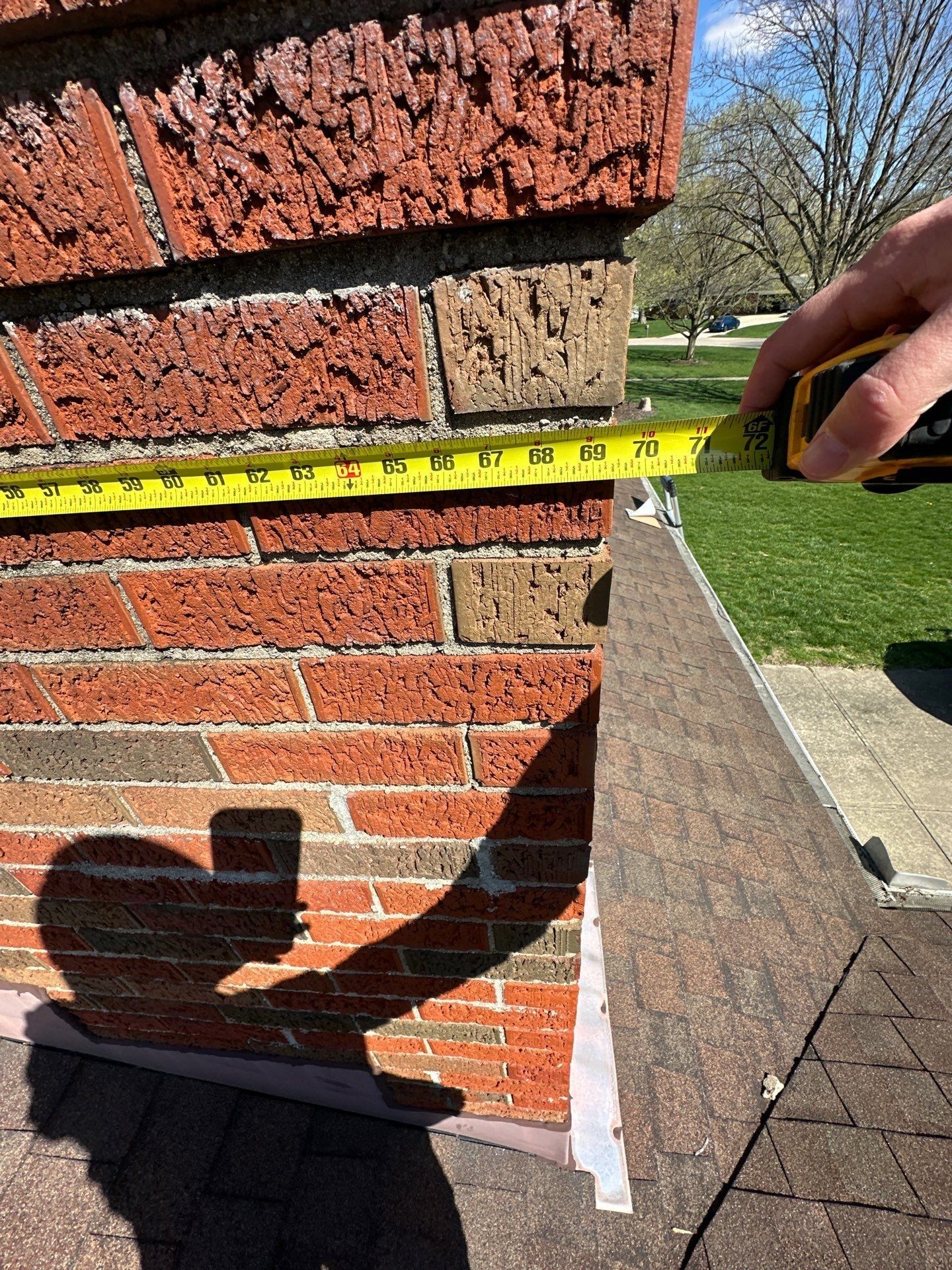 Tape measure along the chimney face to size the new flashing, Beavercreek, Ohio.