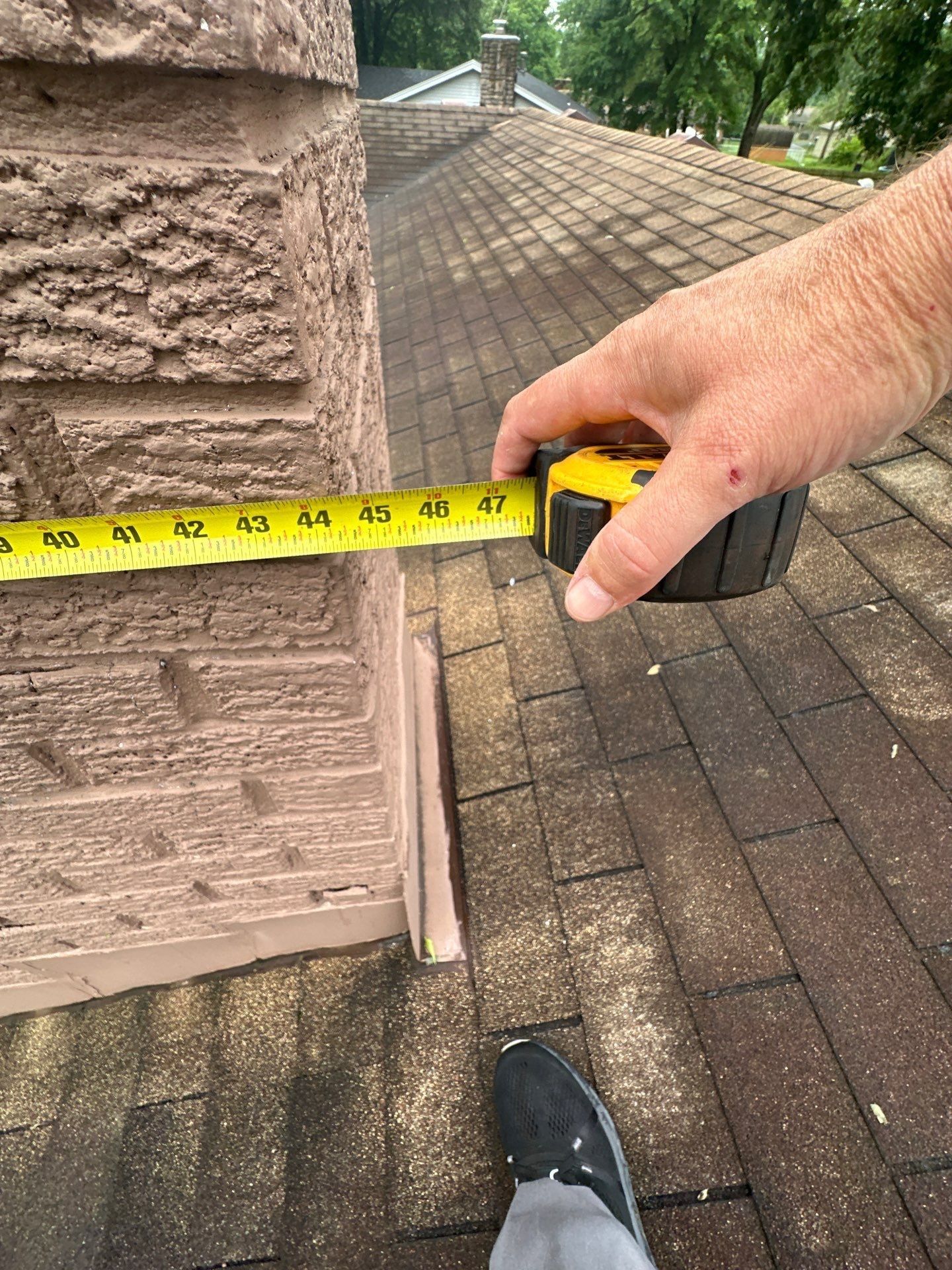 Tape measure sizing the chimney width at the roof line, Beavercreek, Ohio.
