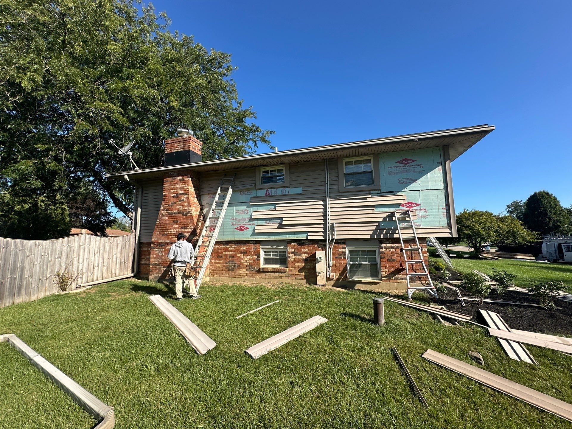 New siding starting up the back wall, with old pieces on the lawn, Beavercreek, Ohio.