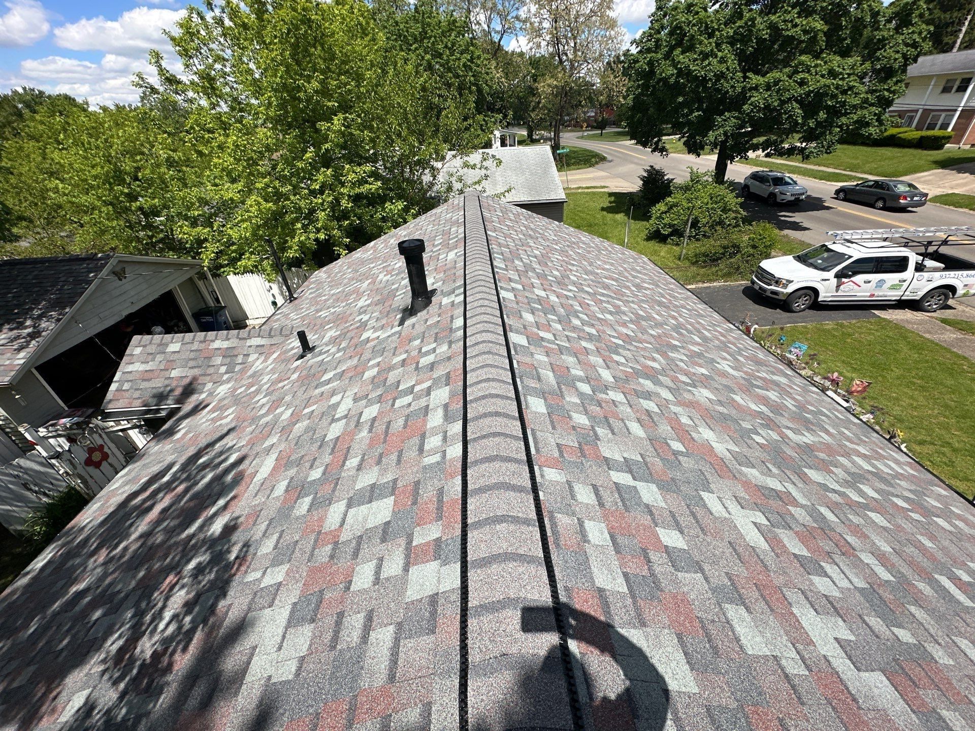 The finished ridge vent and new shingles seen past the front of the house, Dayton, Ohio.