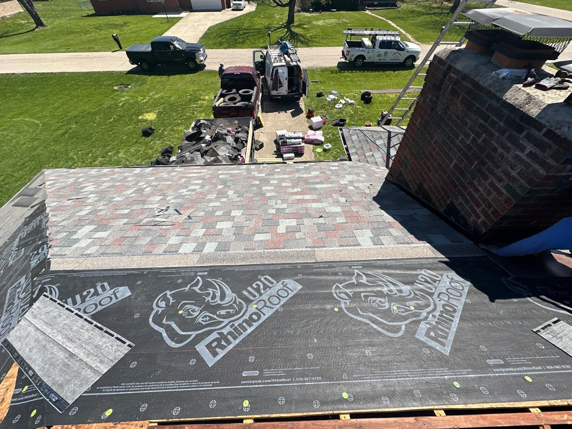 New shingles run up to the brick chimney ahead of the rest of the slope, Beavercreek, Ohio.