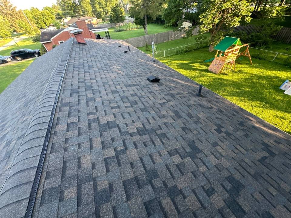 Long finished slope of Peppercorn shingles with ridge vent and box vents, Beavercreek, Ohio.