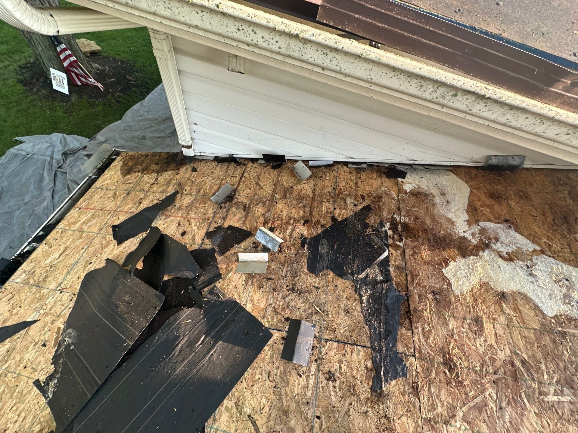 Dark water stains on the lower roof's deck below the house wall, after tear-off, Dayton, Ohio.
