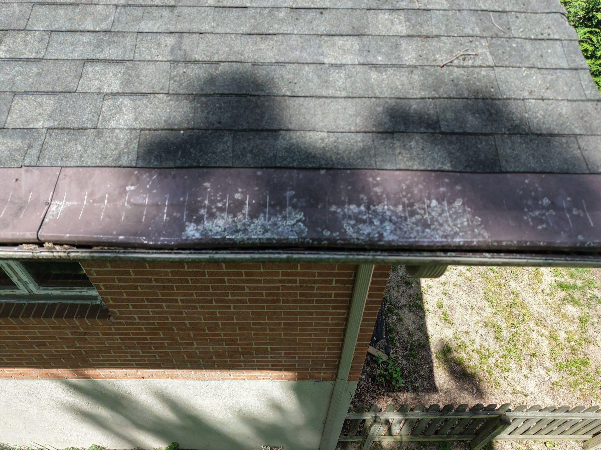 The dented roof edge and gutter line along the brick wall, Beavercreek, Ohio.