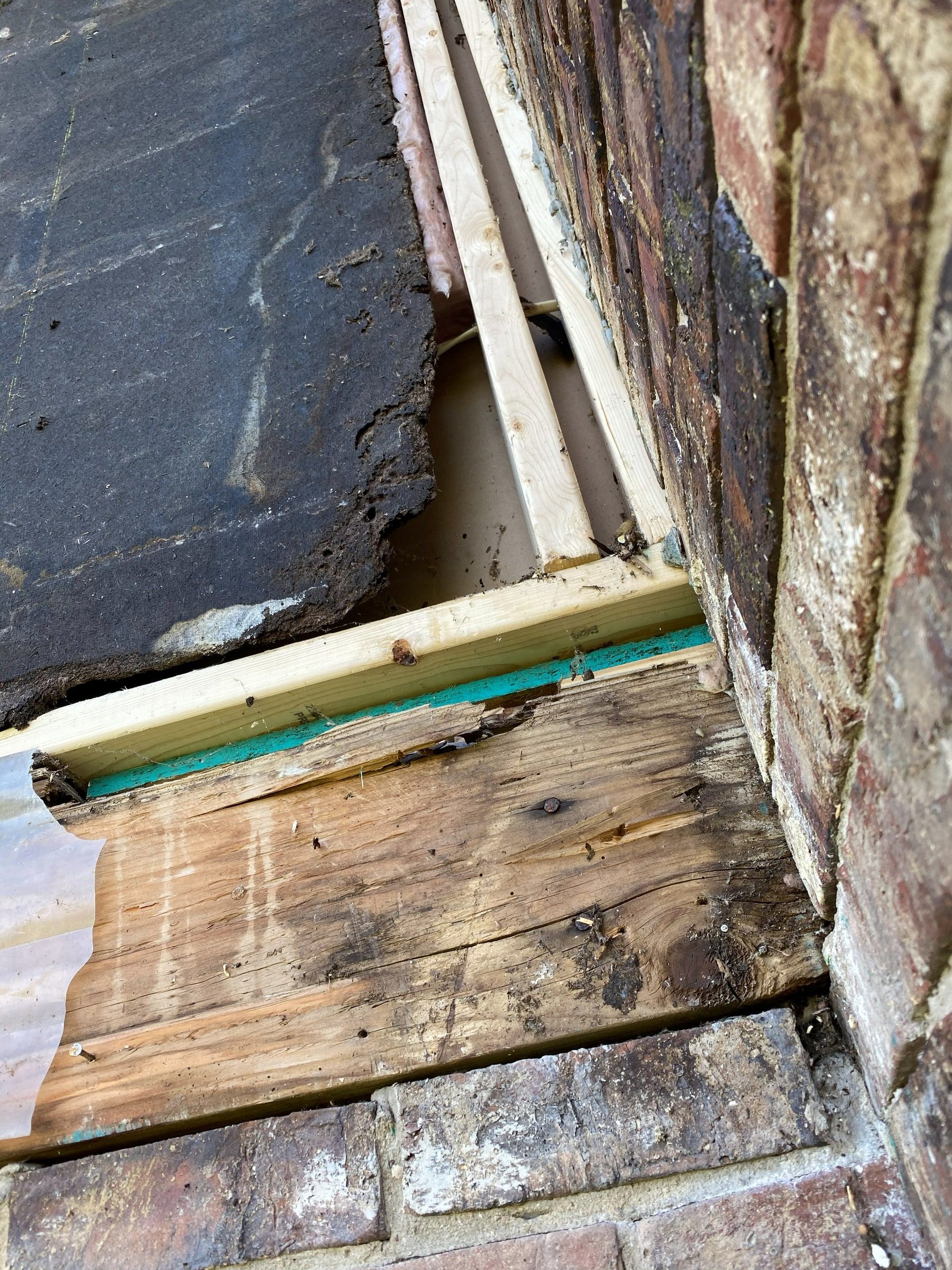 Rotted wood and broken builder board where the wall meets the brick, Beavercreek, Ohio.