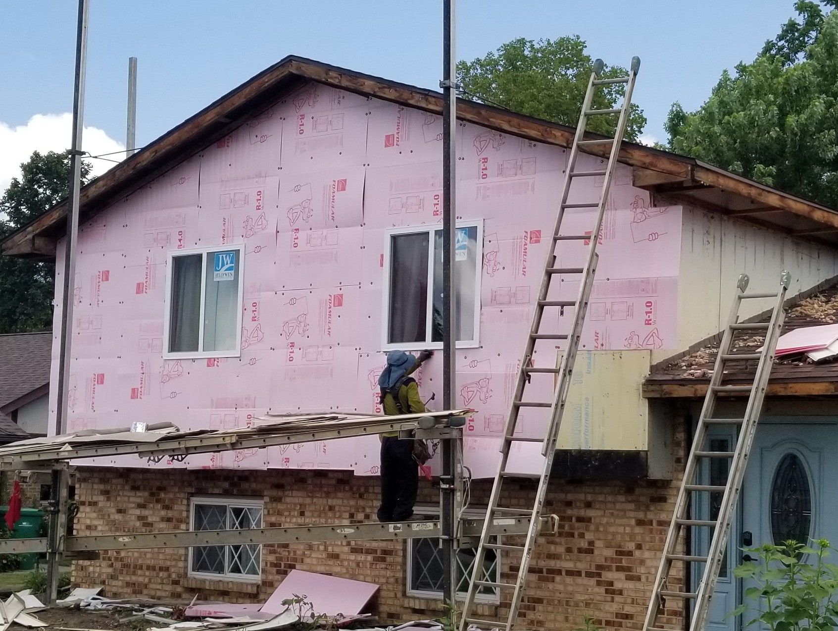 Pink fanfold insulation board on the upper wall, with a crew member on the scaffold, Beavercreek, Ohio.