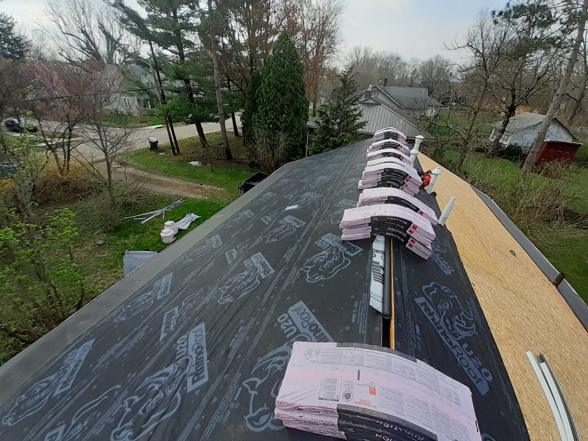 Owens Corning Duration bundles staged along the ridge on new underlayment, with bare OSB on the far slope, Yellow Springs, Ohio.