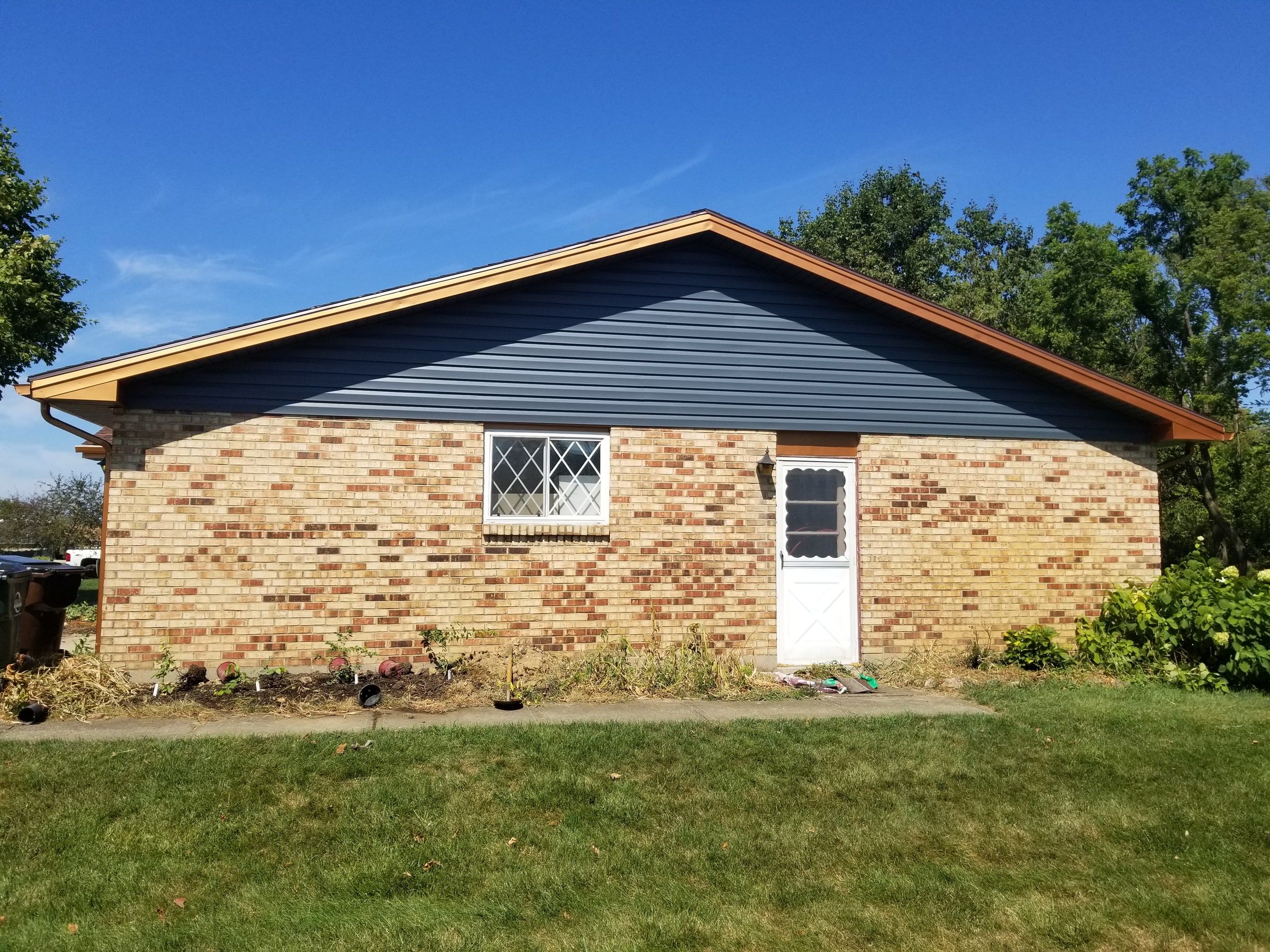 The side gable in blue-gray siding above the brick, Beavercreek, Ohio.