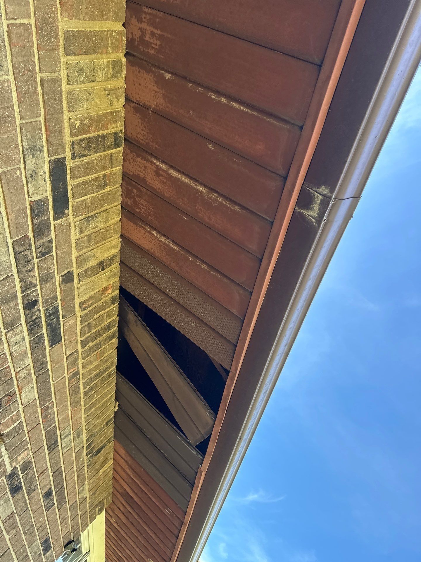 Soffit missing under the eave beside the brick wall, Xenia, Ohio.