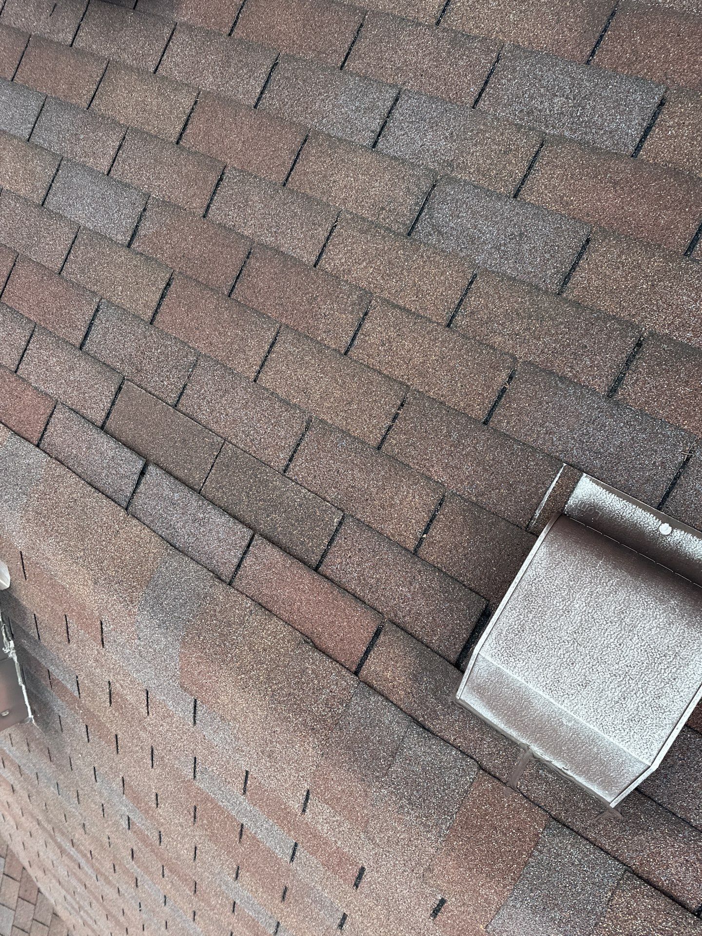 A metal roof vent hood bent up on the old shingles, Beavercreek, Ohio.